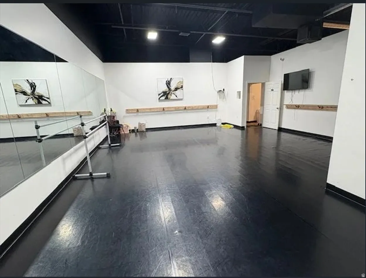 Spacious interior room featuring dark flooring, white walls, and a black ceiling