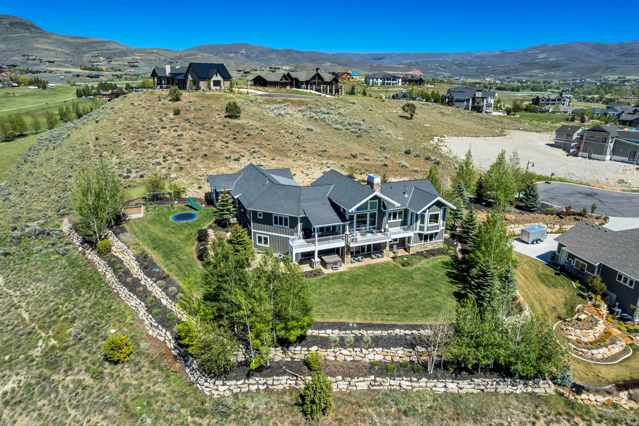 Expansive gray-sided residence featuring a multi-level deck, dark shingle roof, and multiple gables