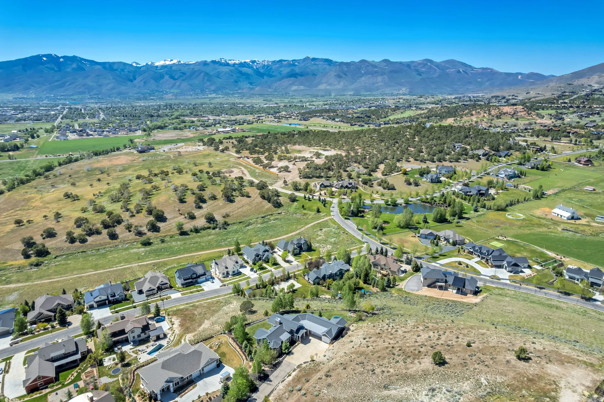 Expansive aerial showcasing a residential community amidst natural terrain with distant snow-capped mountains