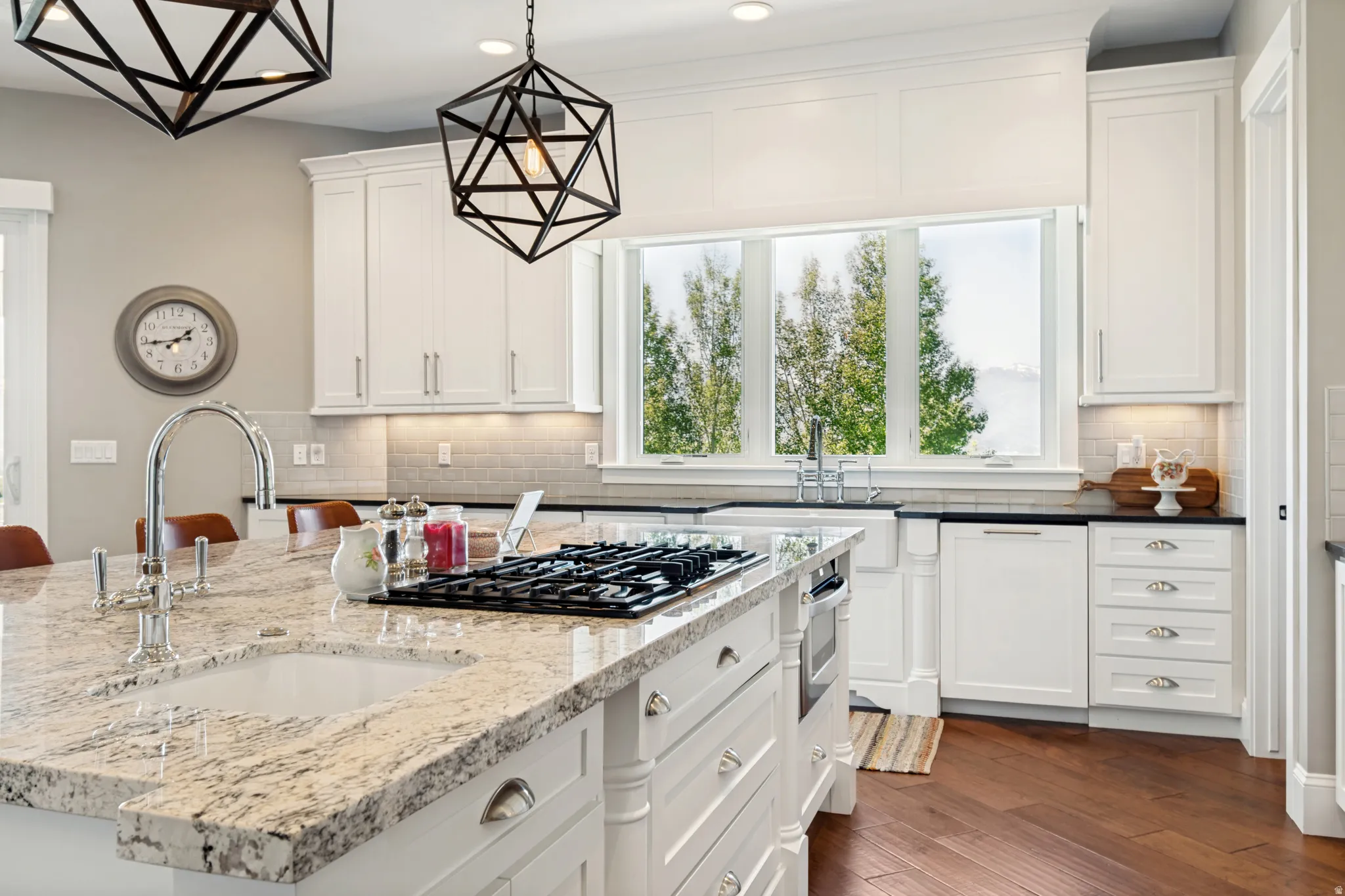 Kitchen island featuring a built-in gas range, dual pendant lighting, and a prep sink with a high-arc faucet