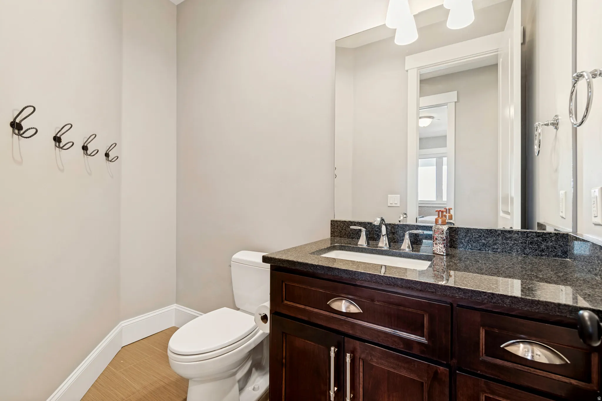 Bathroom featuring a wood-finish vanity with an undermount sink, dark stone countertop, and brushed nickel fixtures