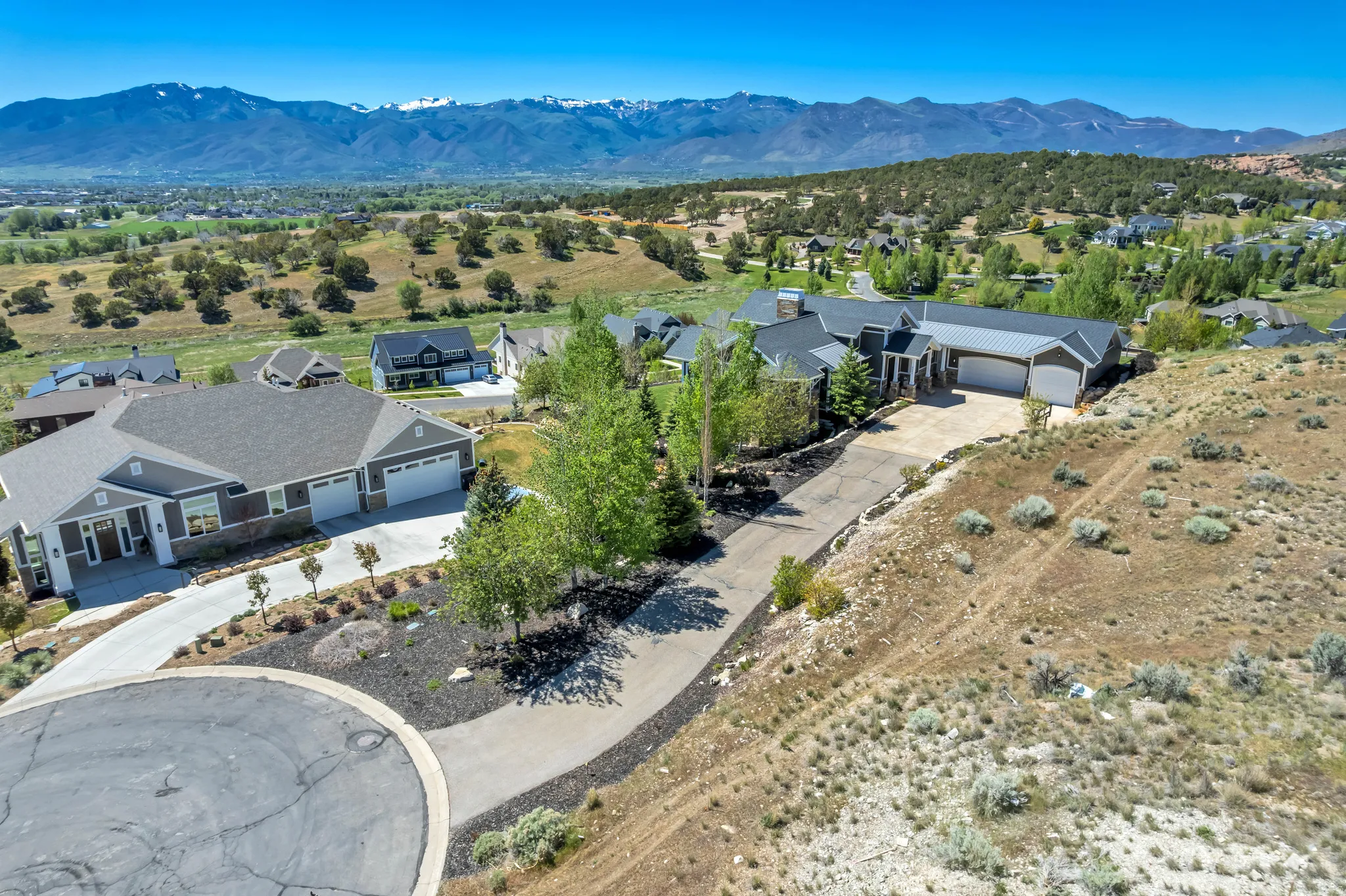 Modern ranch-style home featuring a dark gray exterior with stone accents and a multi-car garage
