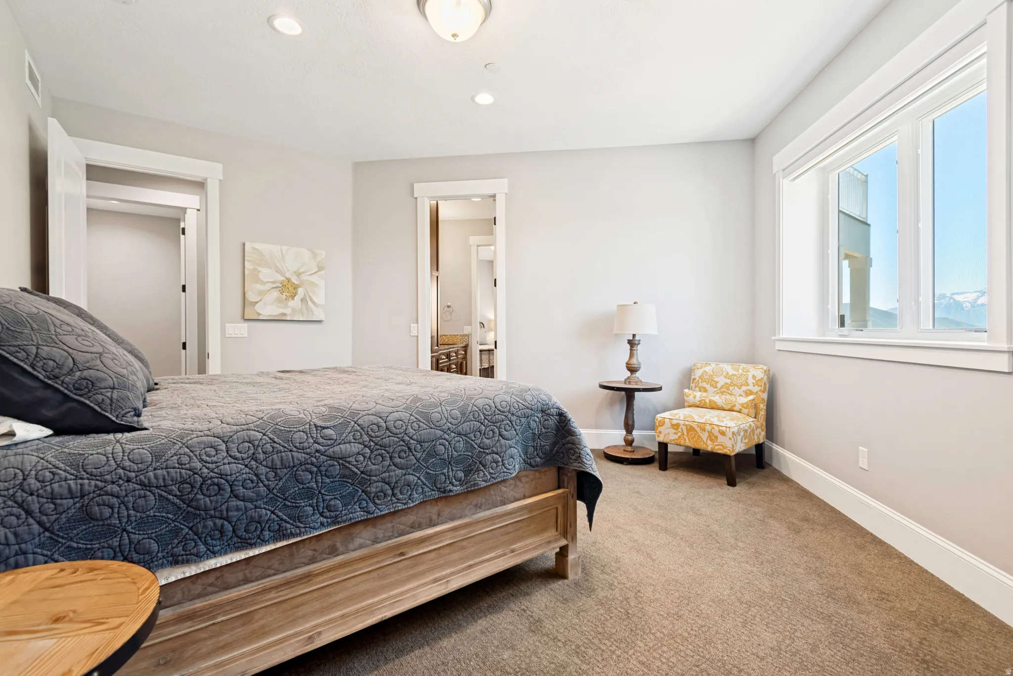 Carpeted bedroom featuring a large window with mountain scenery, recessed lighting, and a wood-finish bed frame
