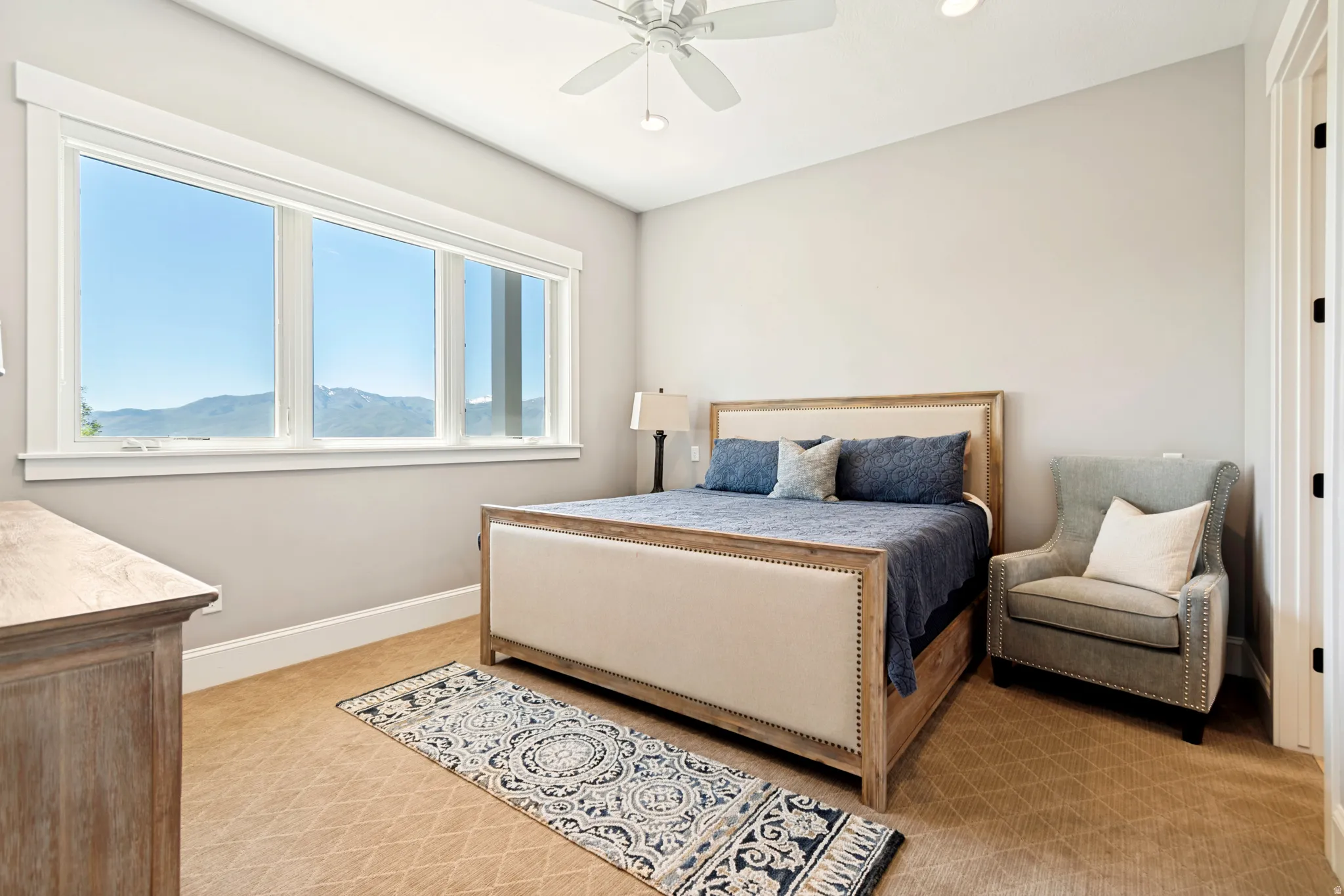 Expansive window offering mountain scenery, complemented by light gray wall paint and textured carpet flooring