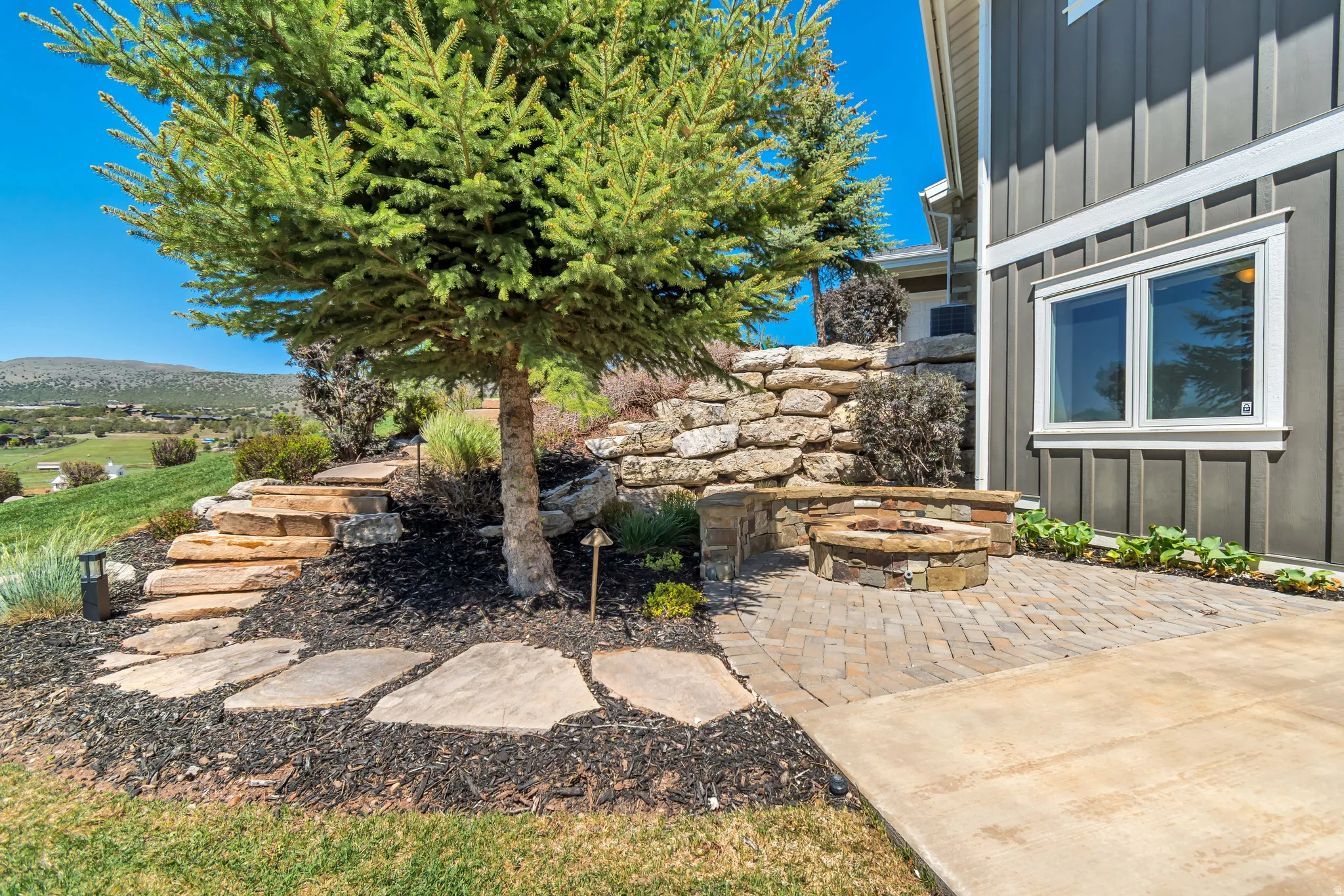 Exterior patio featuring a built-in stone fire pit, paver flooring, and concrete hardscaping