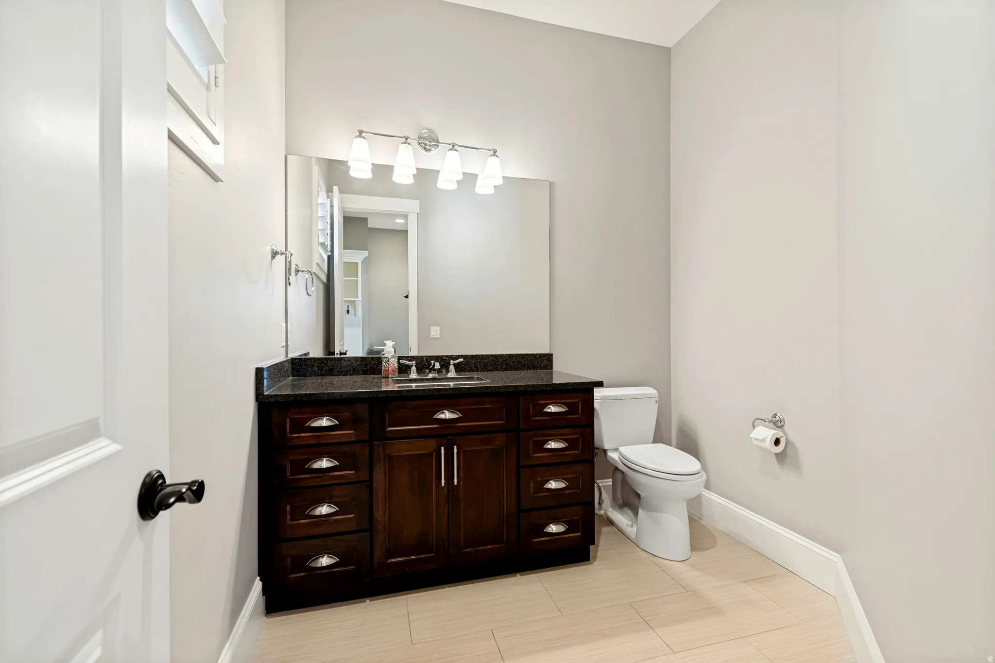 Bathroom featuring a dark wood vanity with ample storage, a dark countertop, and a single basin sink