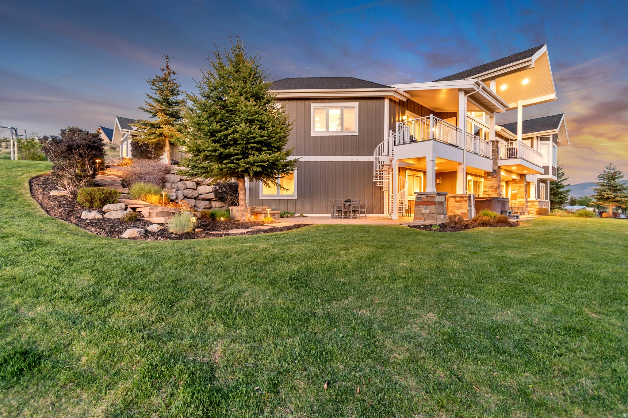 Expansive rear exterior featuring multiple balconies, a spiral staircase, and a ground-level patio
