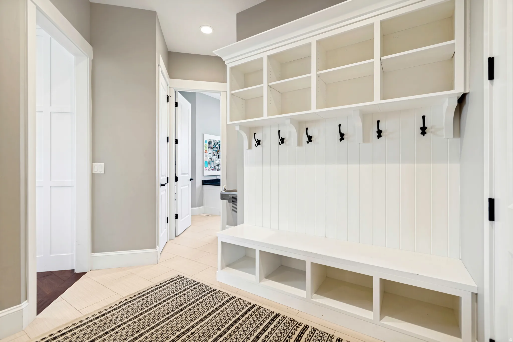 Built-in white storage unit featuring upper shelving, coat hooks, and a lower bench with cubbies