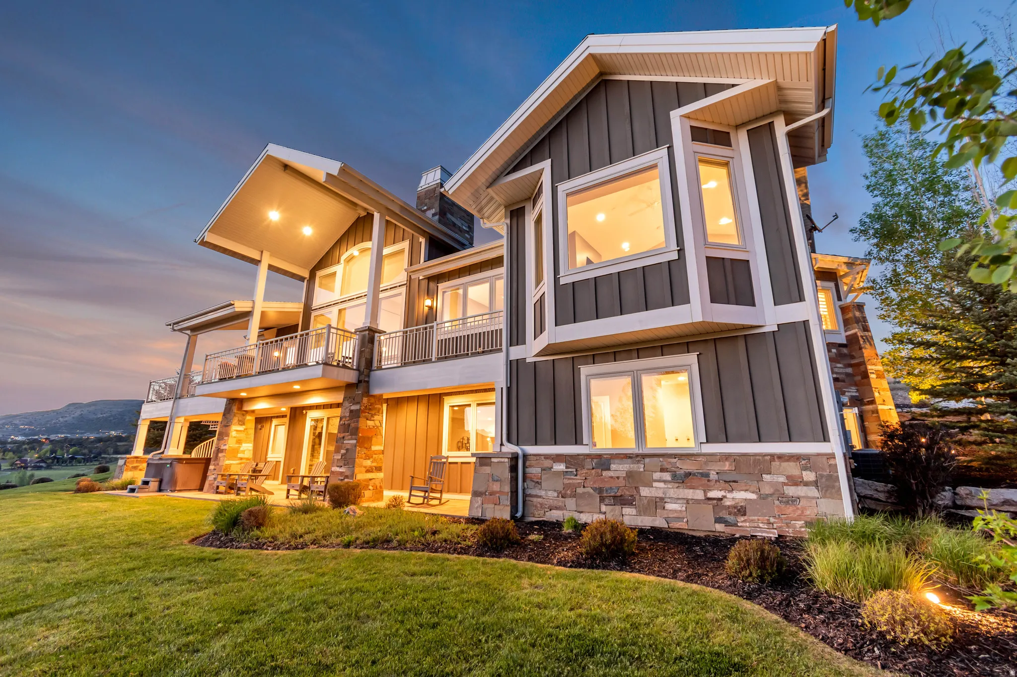 Multi-level residence featuring a stone and siding exterior with multiple balconies and a ground-level patio