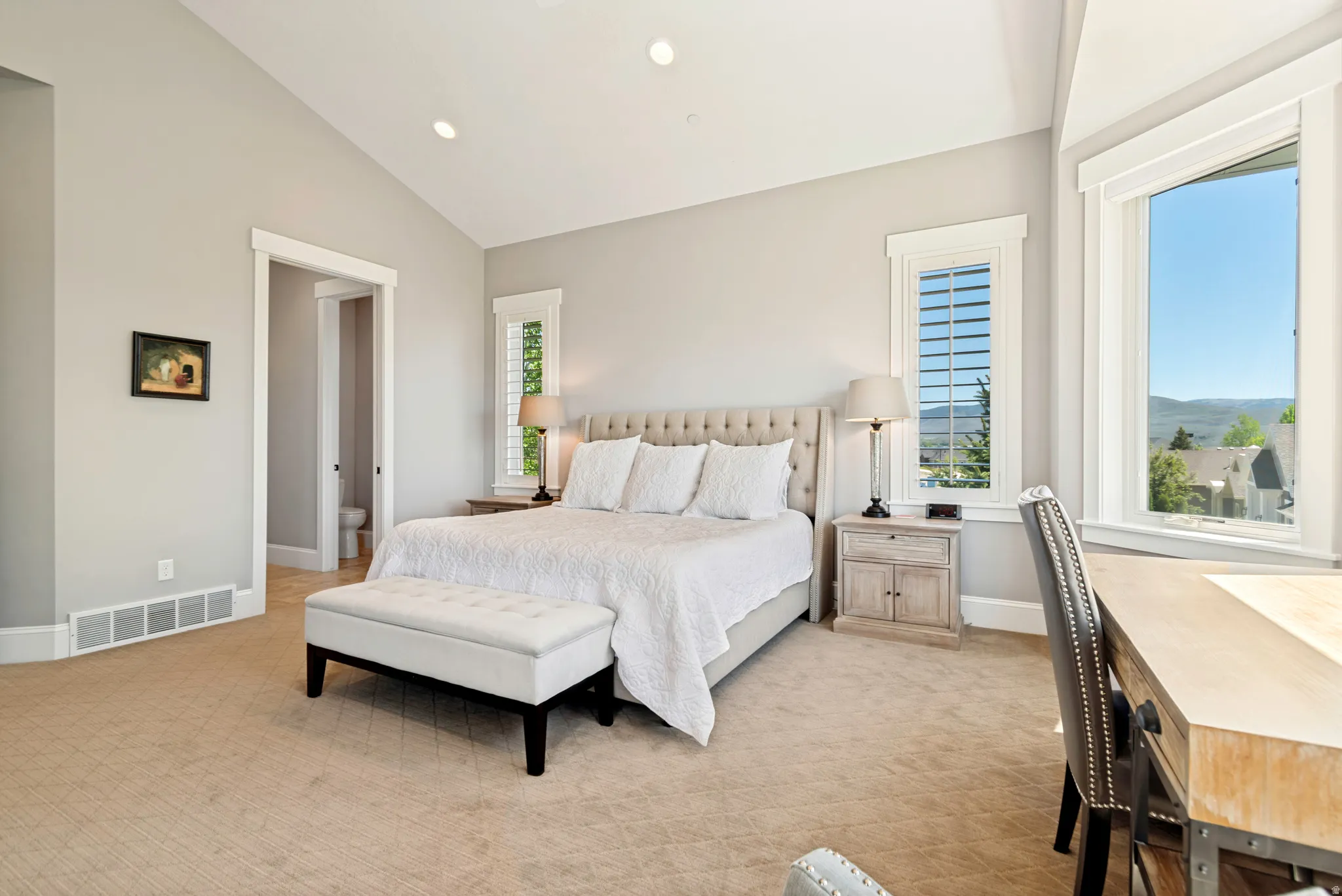 Vaulted ceiling bedroom featuring recessed lighting, extensive neutral carpeting, and a large window with a distant landscape
