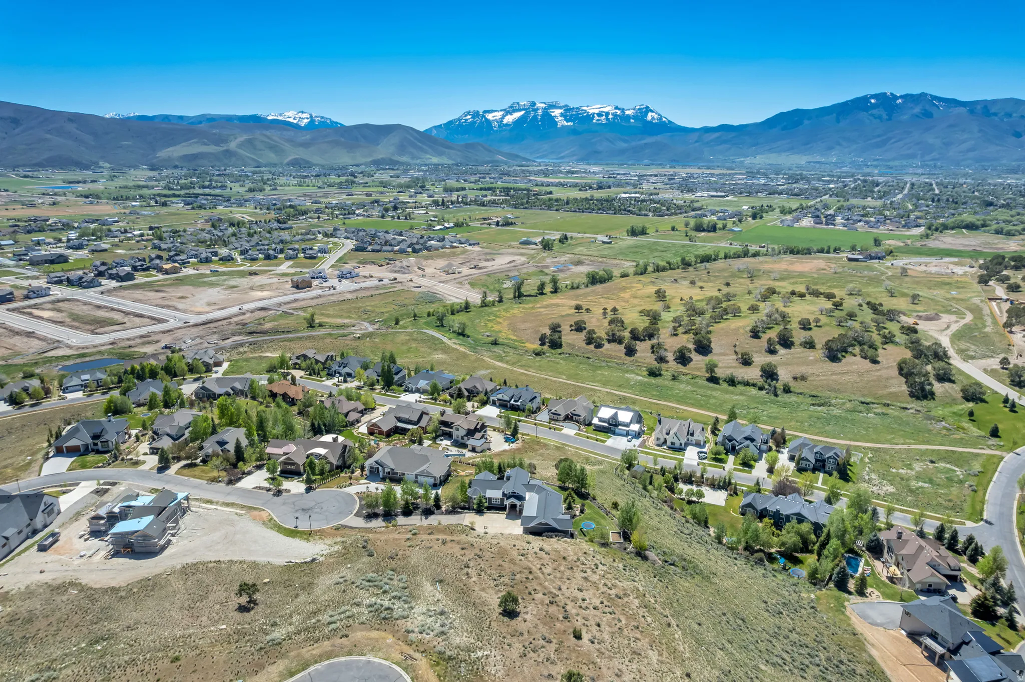 Expansive aerial perspective showcasing a residential community amidst rolling hills and green pastures