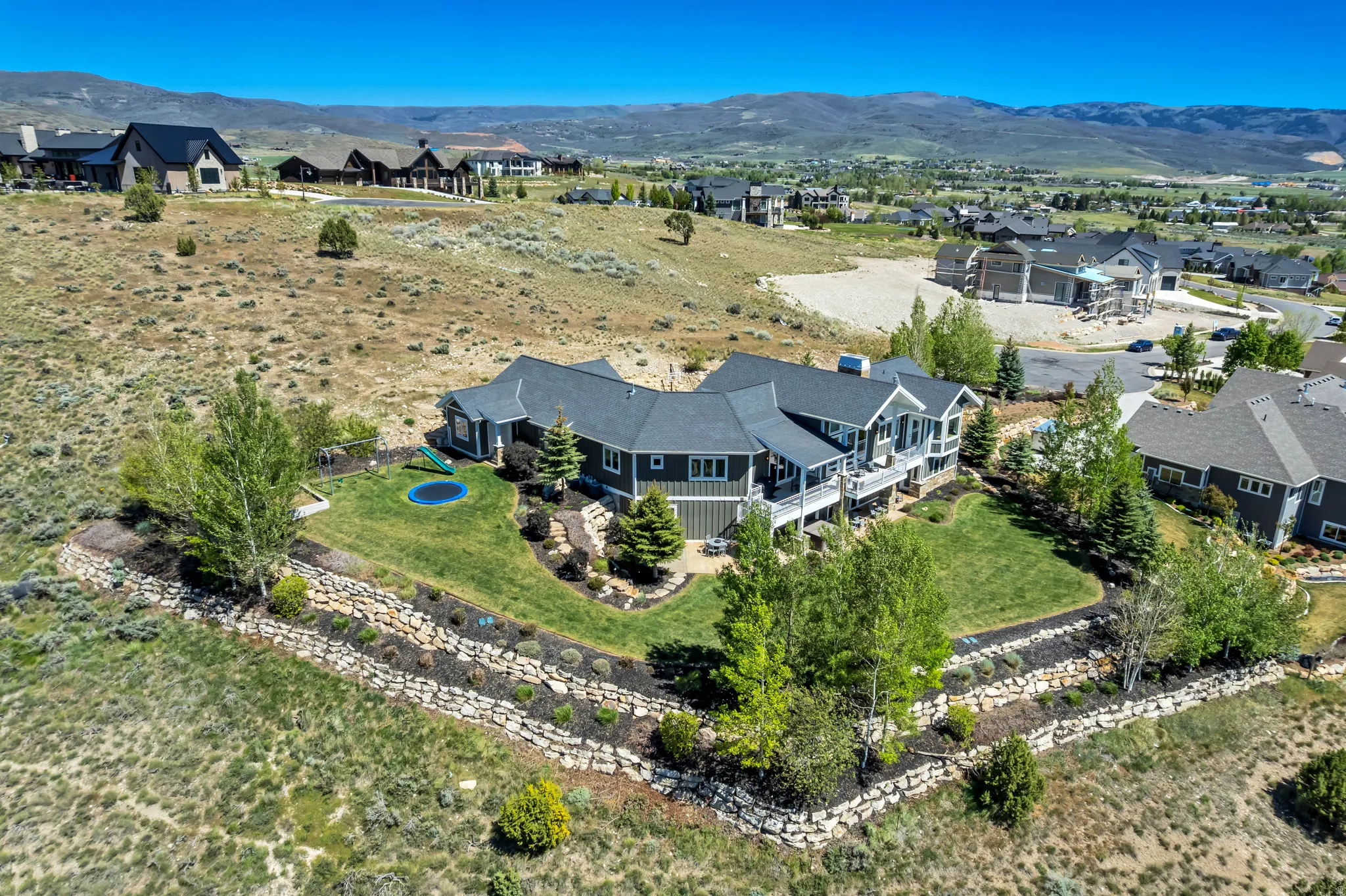Expansive property featuring a multi-level residence with dark siding and a prominent dark roof