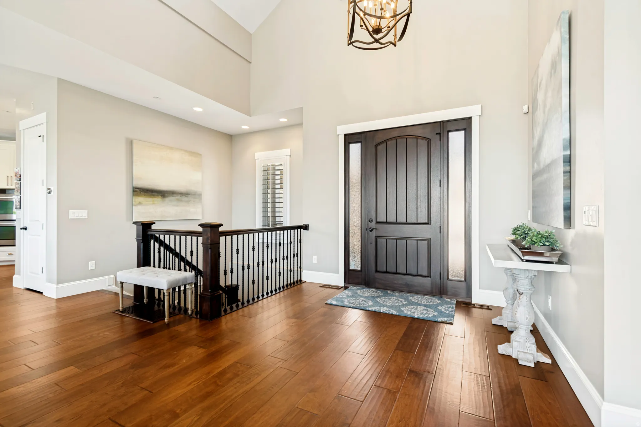 Grand entryway featuring a high ceiling, wood-finish flooring, and a dark wood front door with sidelights