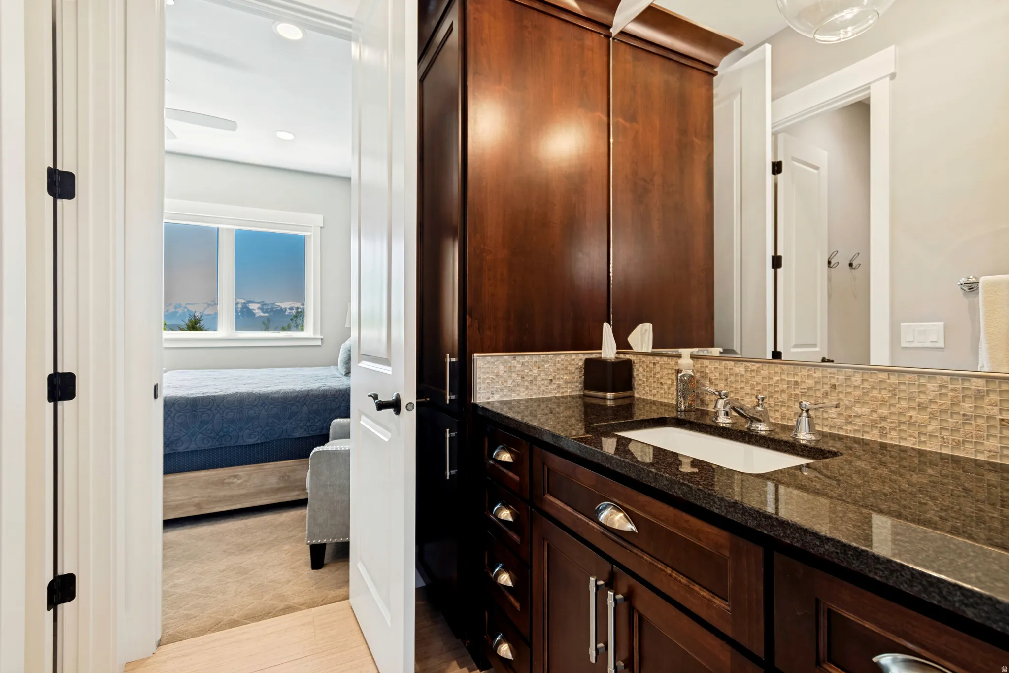 Bathroom vanity featuring a dark wood-finish cabinet, a polished stone countertop, a rectangular undermount sink, and a tiled backsplash