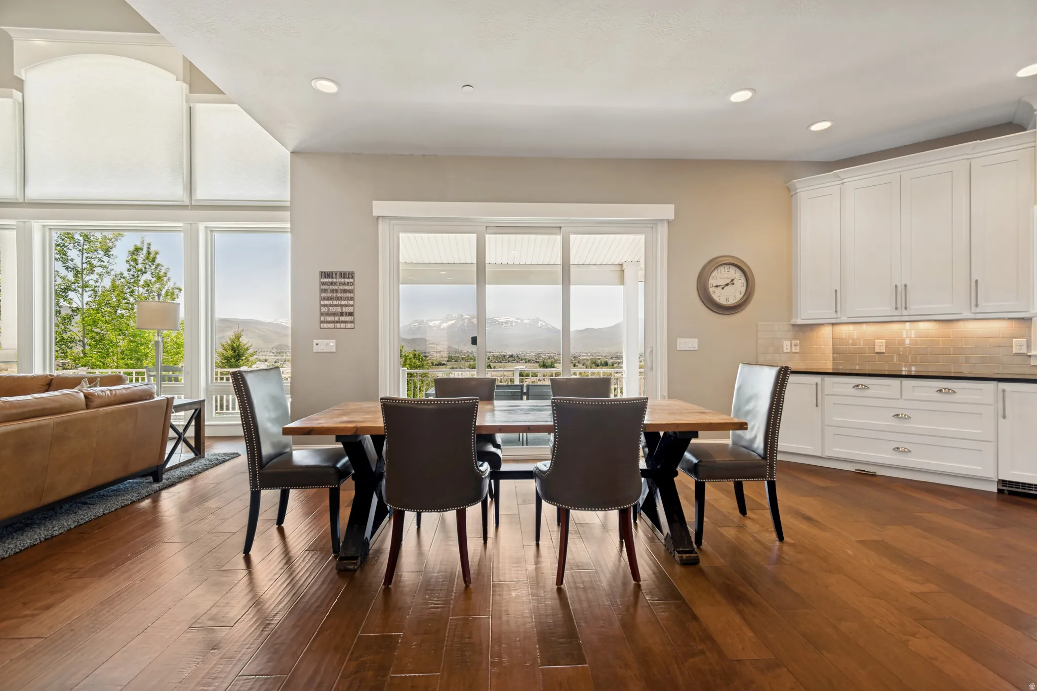 Open-concept living space featuring wood-finish flooring, white cabinetry, and a sliding glass door opening to an outdoor area with mountain scenery