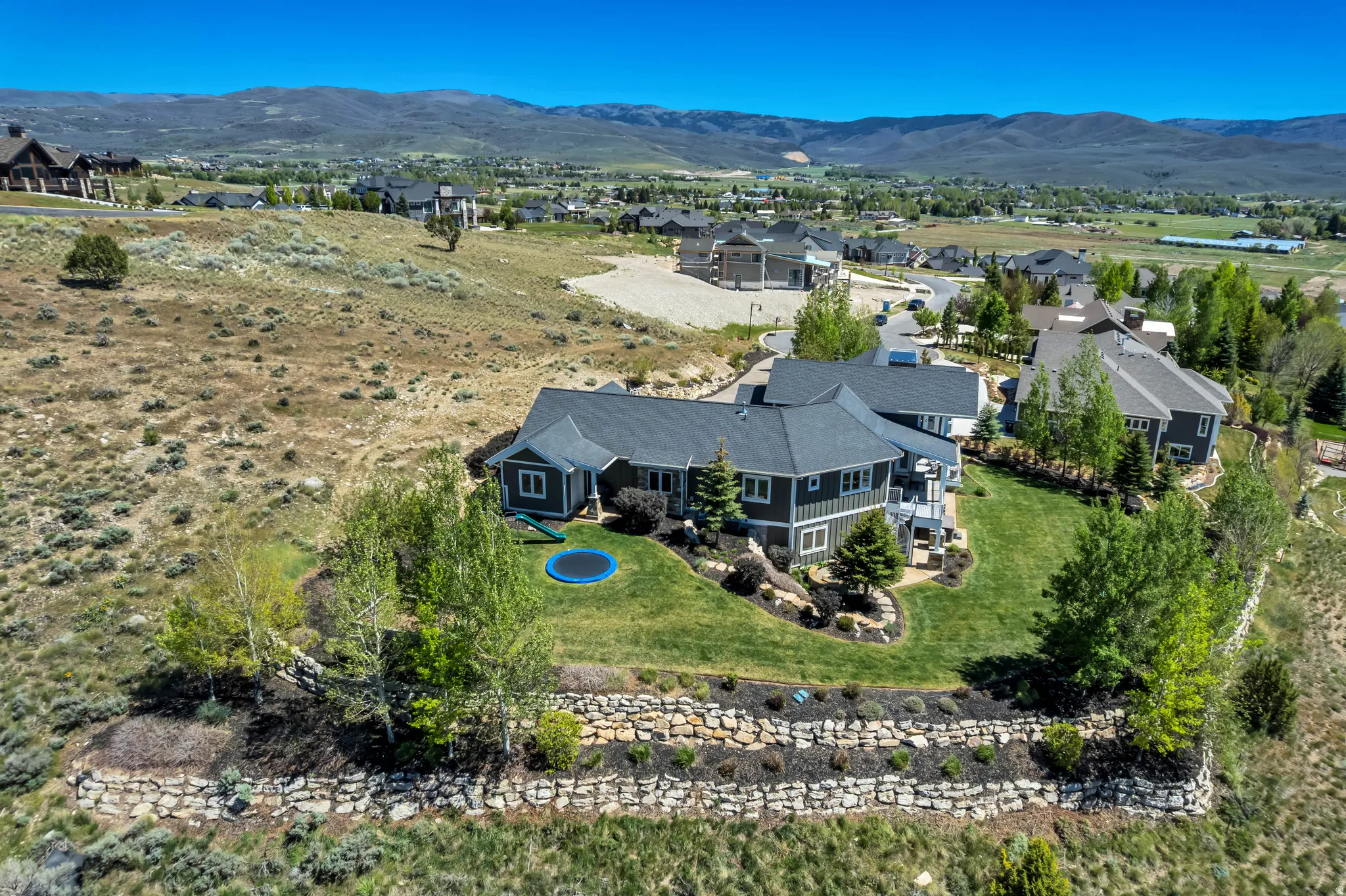 Expansive residential property featuring a multi-level dwelling with dark siding and a dark shingle roof