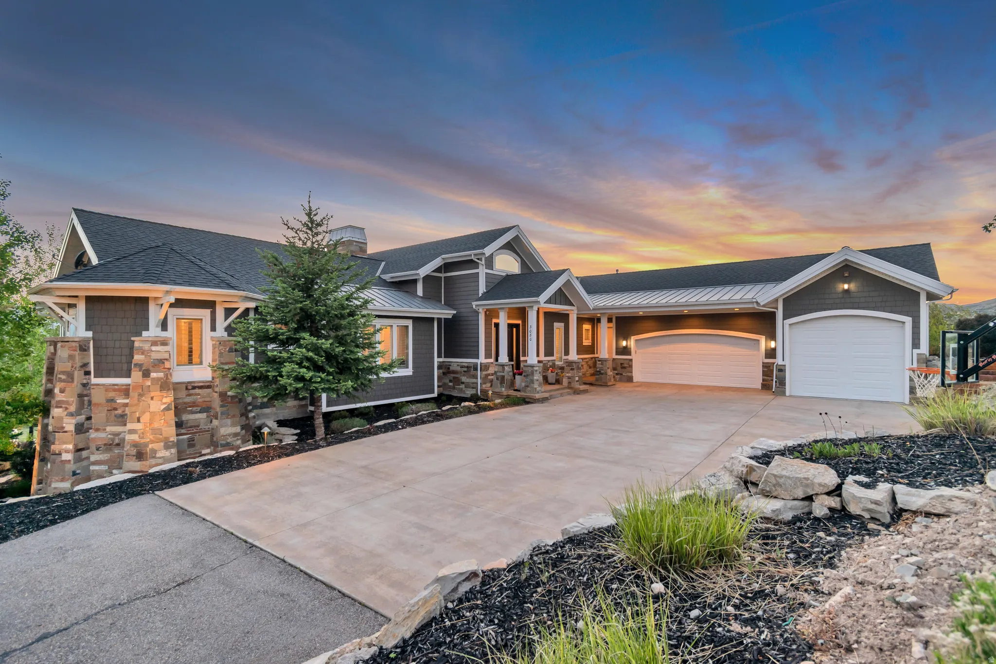 Craftsman-style exterior featuring a multi-gable roofline, stone veneer accents, wood-shake siding, and a concrete driveway
