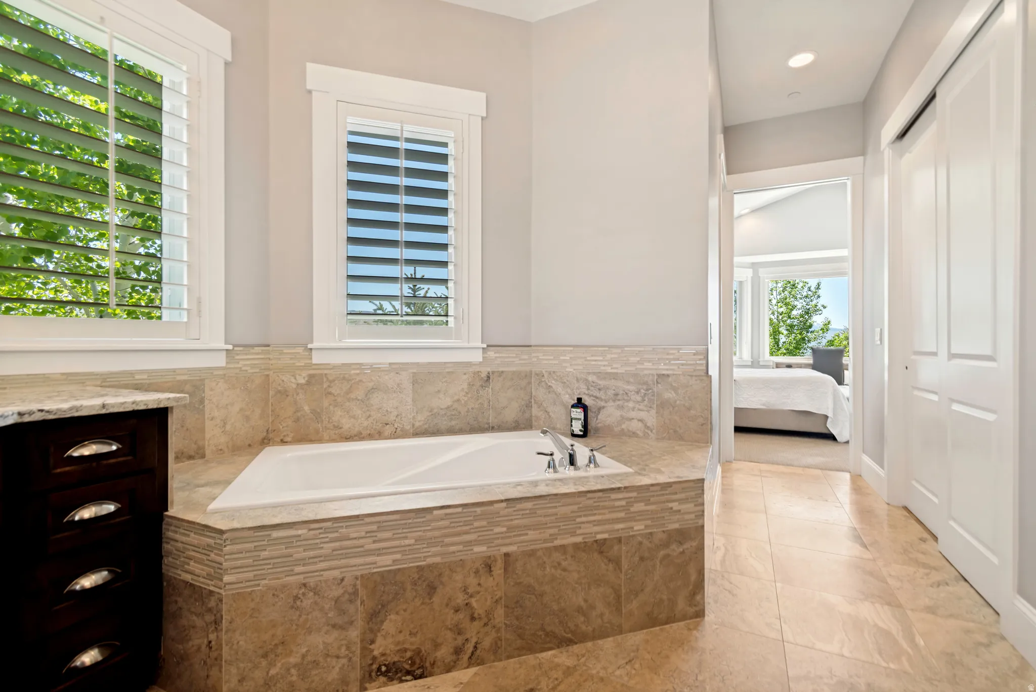 Built-in soaking tub with stone surround featuring mosaic tile accents
