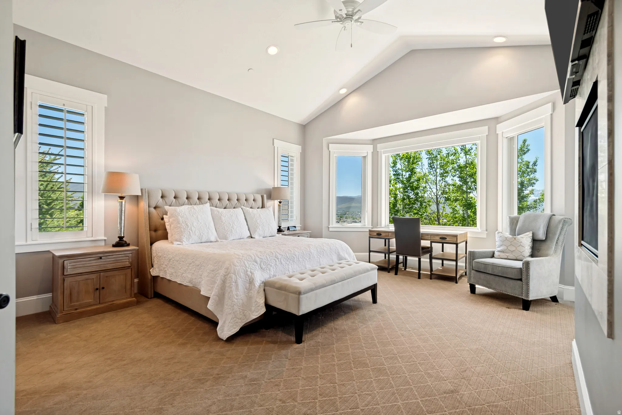 Spacious room featuring vaulted ceilings, a large bay window, recessed lighting, and patterned carpeting