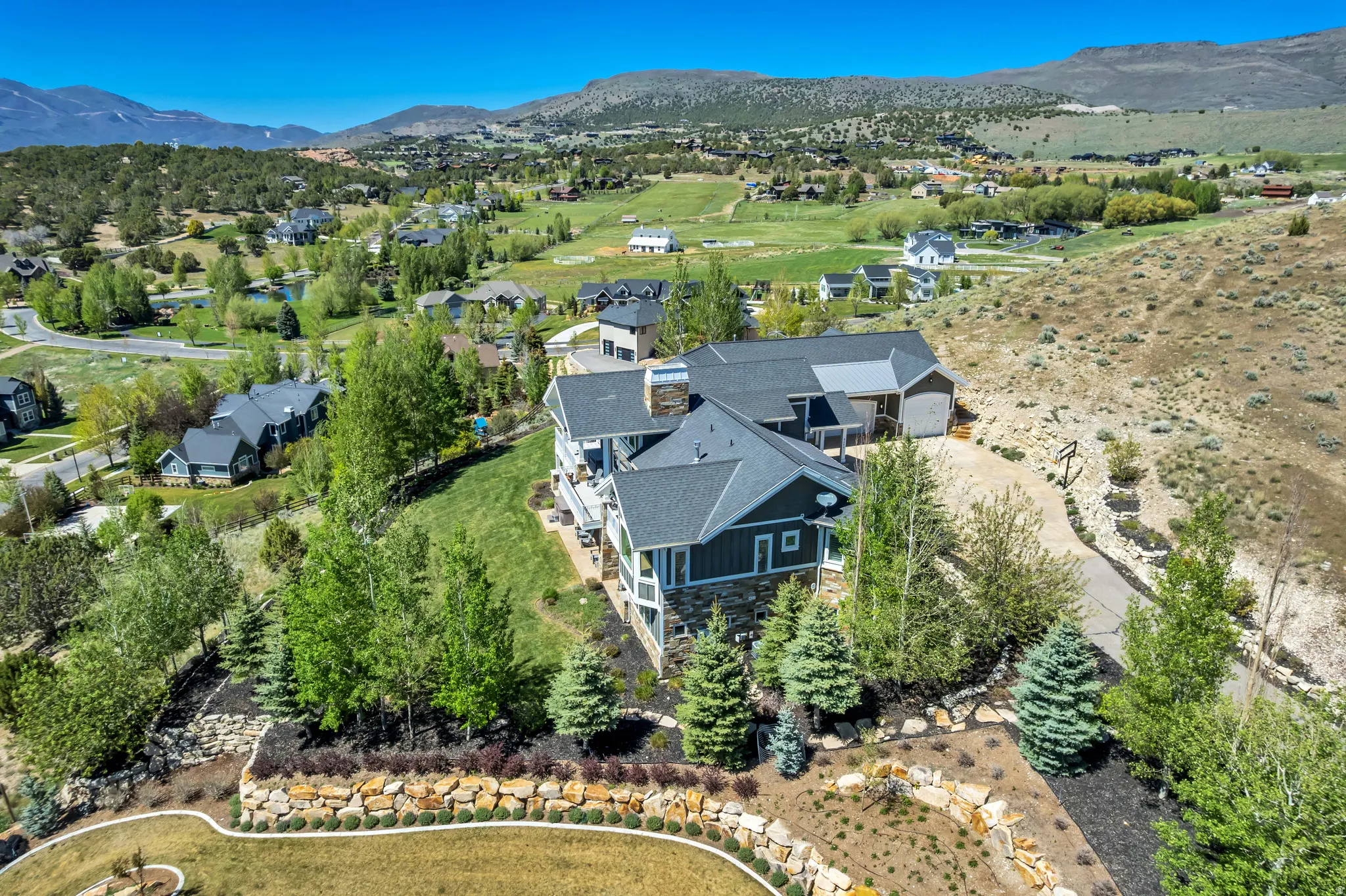 Expansive property featuring a multi-story residence with dark siding and stone accents