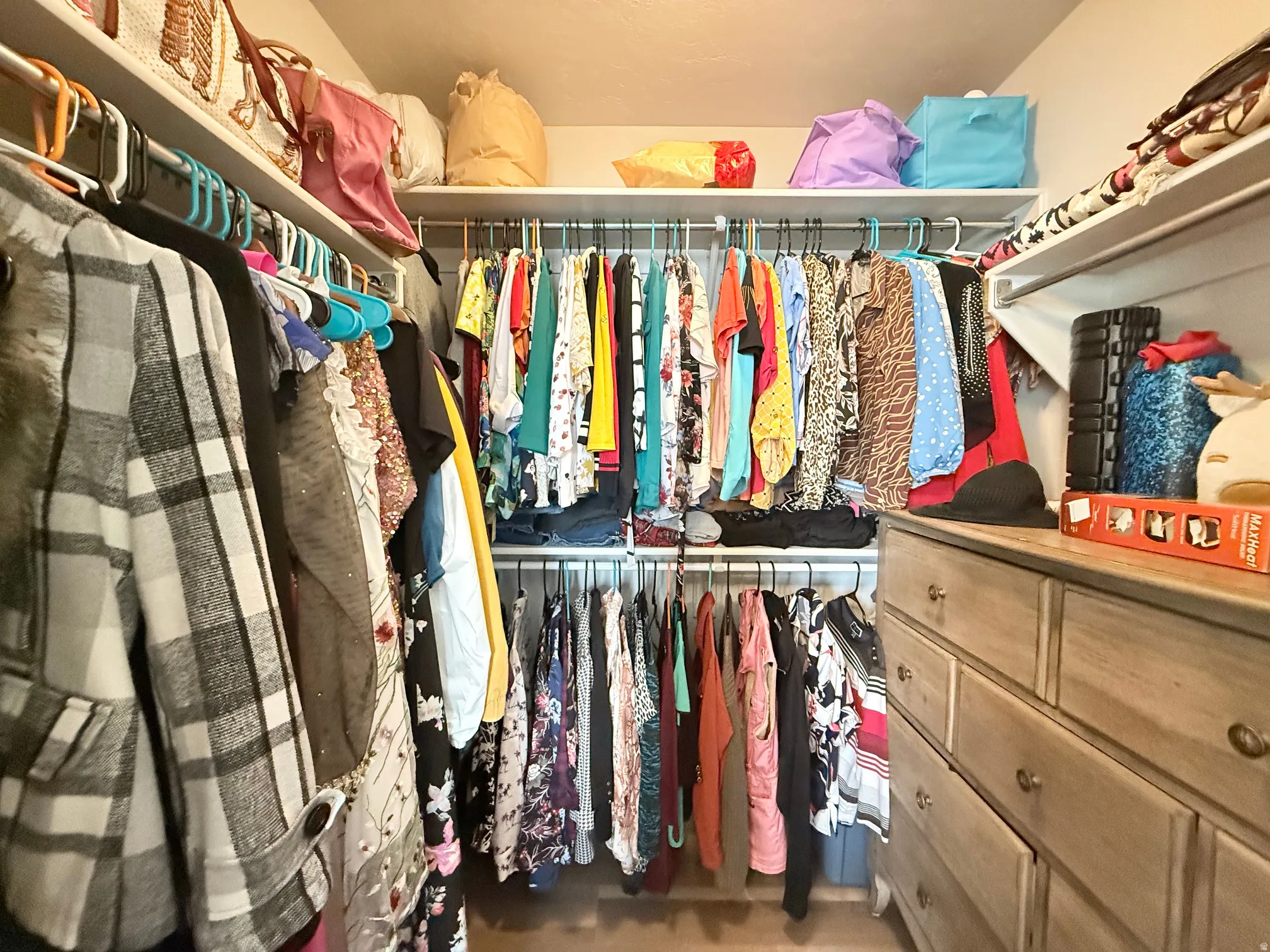 Walk-in closet featuring built-in shelving, multiple hanging rods, and wood-finish flooring