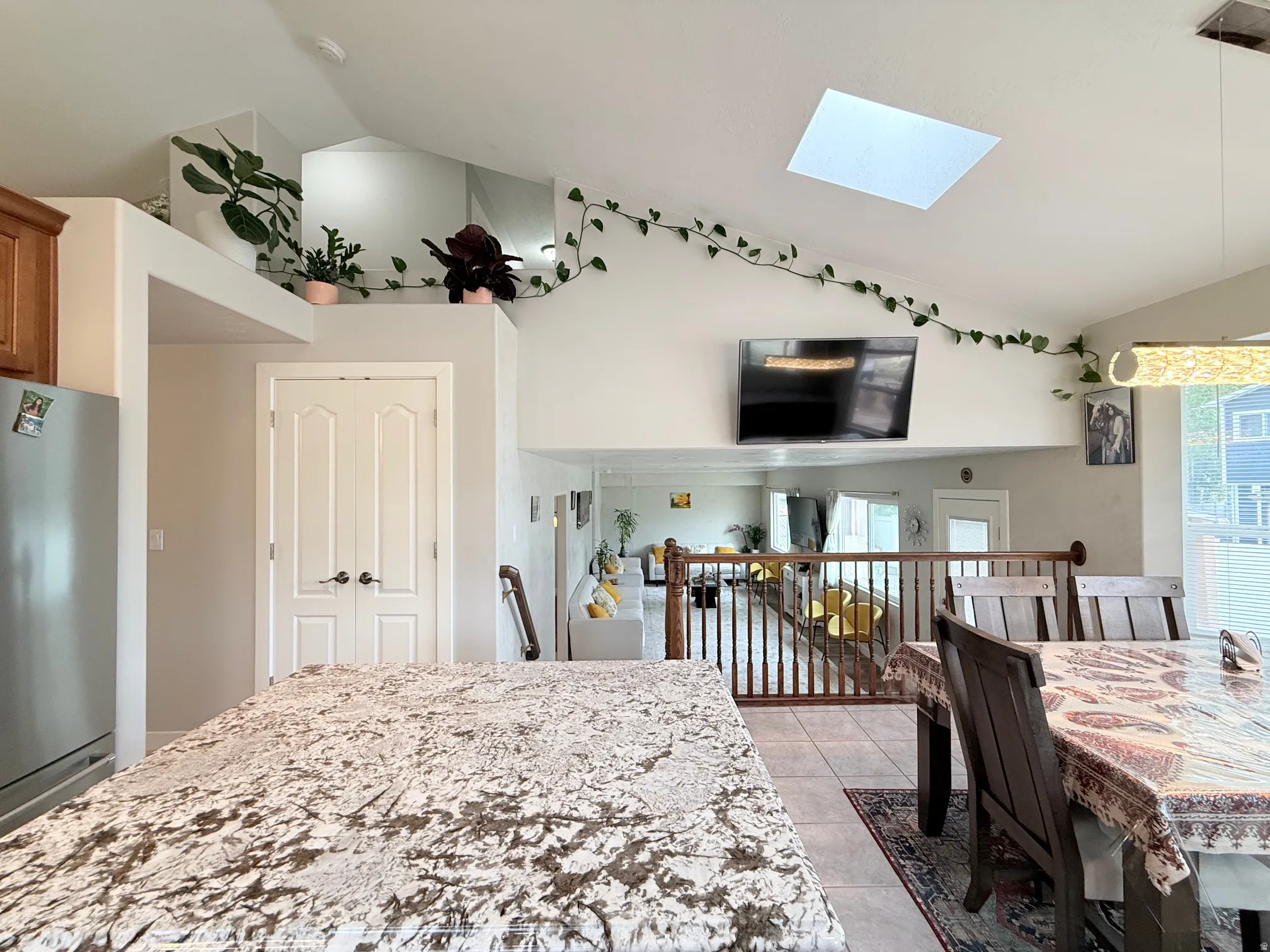 Open-concept living space featuring a granite-finish kitchen island, an overhead skylight, and a dining area with a modern chandelier