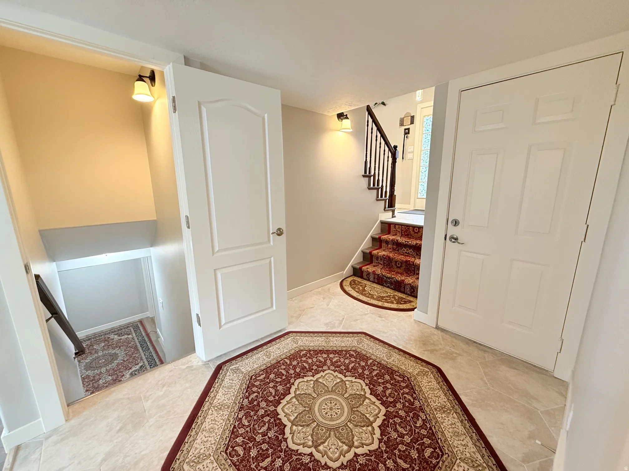 Entryway featuring neutral-toned tile flooring, two paneled doors, and a staircase with dark wood banister and white spindles