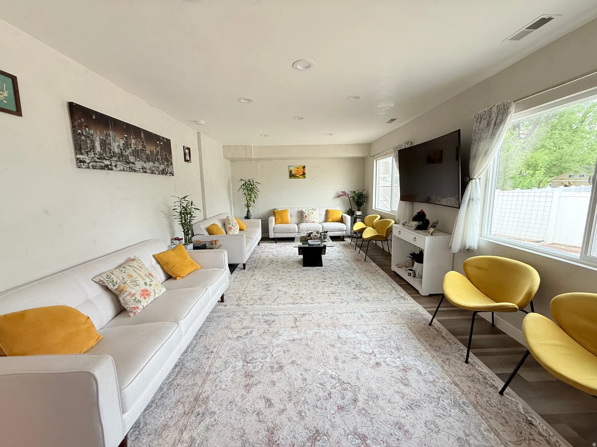 Spacious living area featuring light-toned walls, recessed lighting, and wood-finish flooring