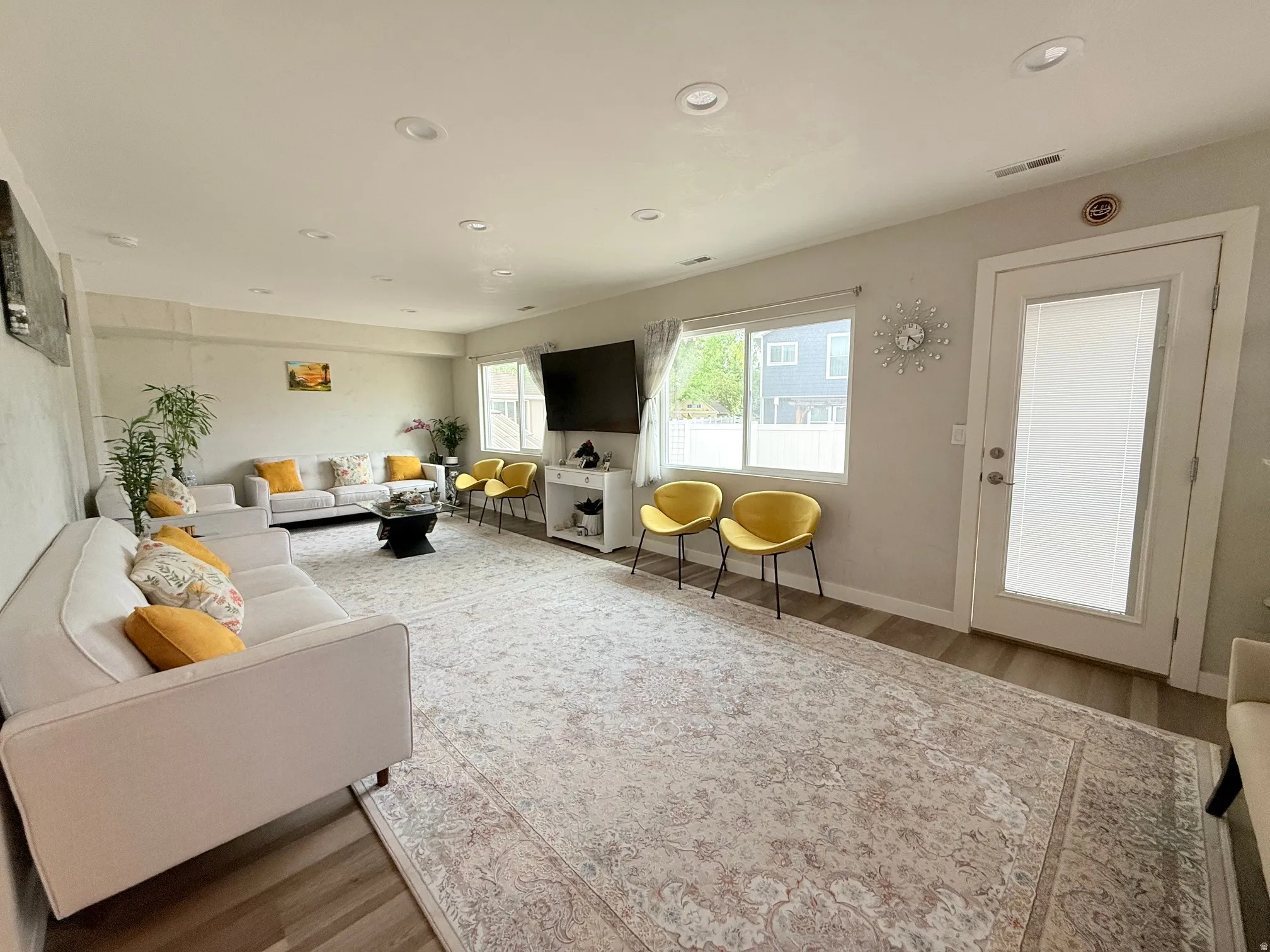Spacious room featuring light-toned walls, recessed lighting, and wood-finish flooring