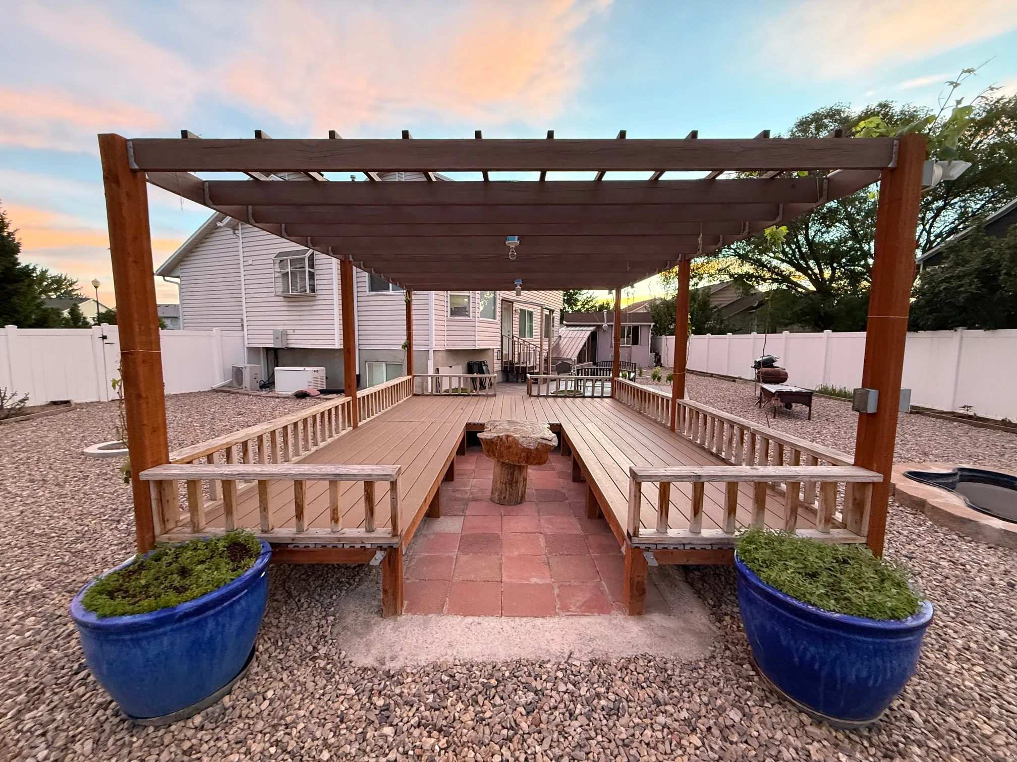 Outdoor pergola structure featuring built-in wood-look decking and seating