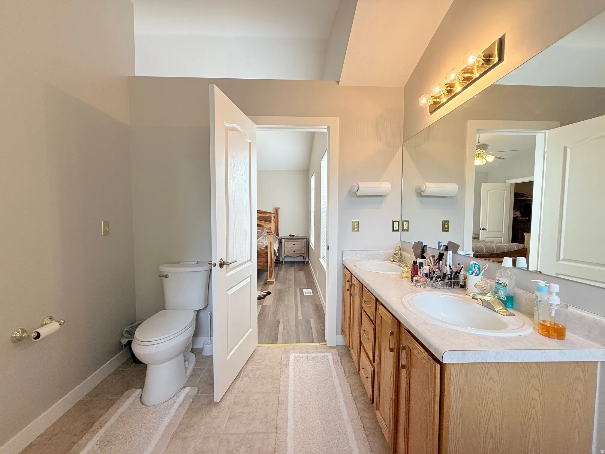 Bathroom featuring a double vanity with light wood cabinetry, dual undermount sinks, and a full-width mirror