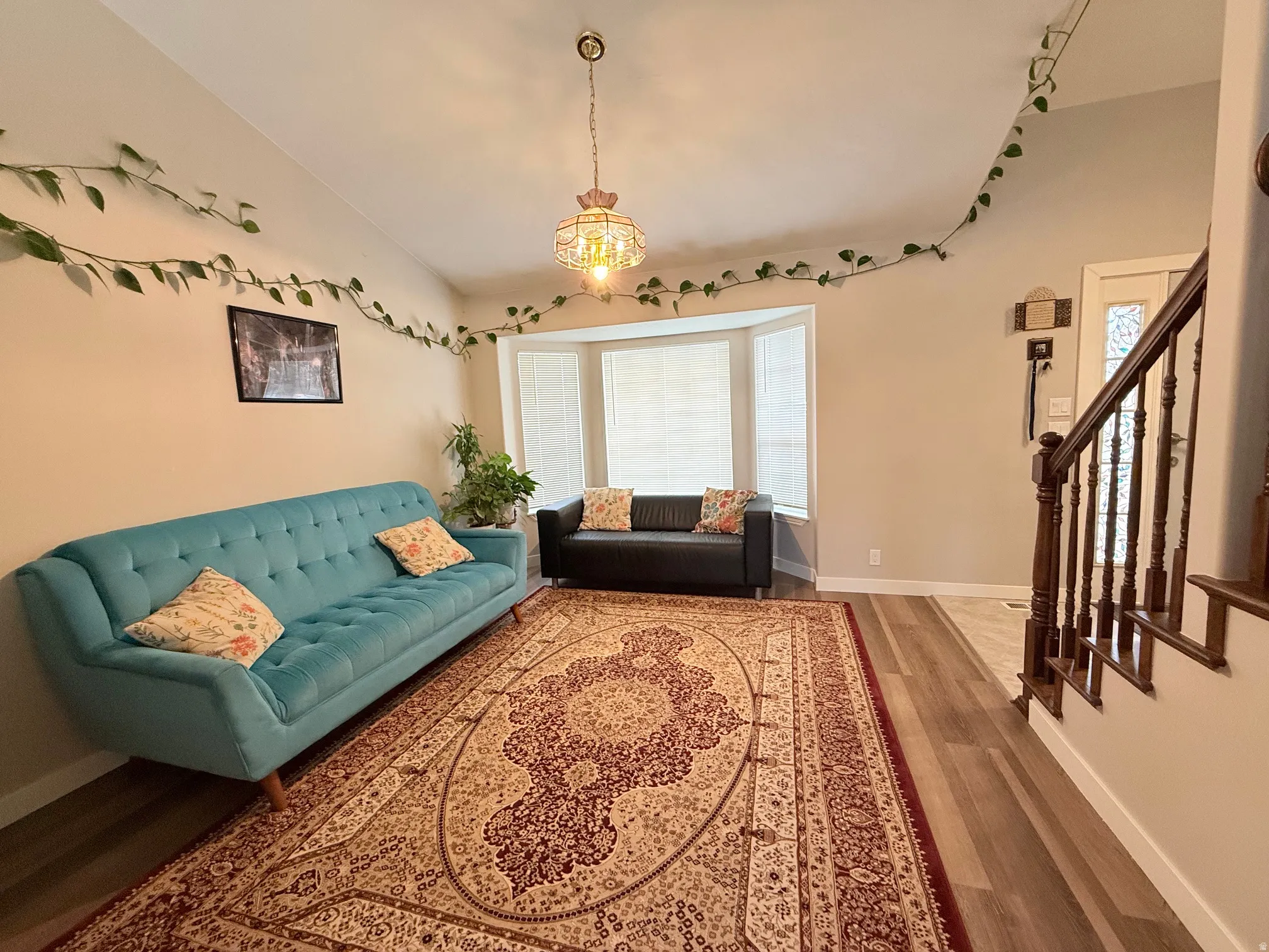 Spacious living area featuring wood-finish flooring, a decorative chandelier, and a bay window