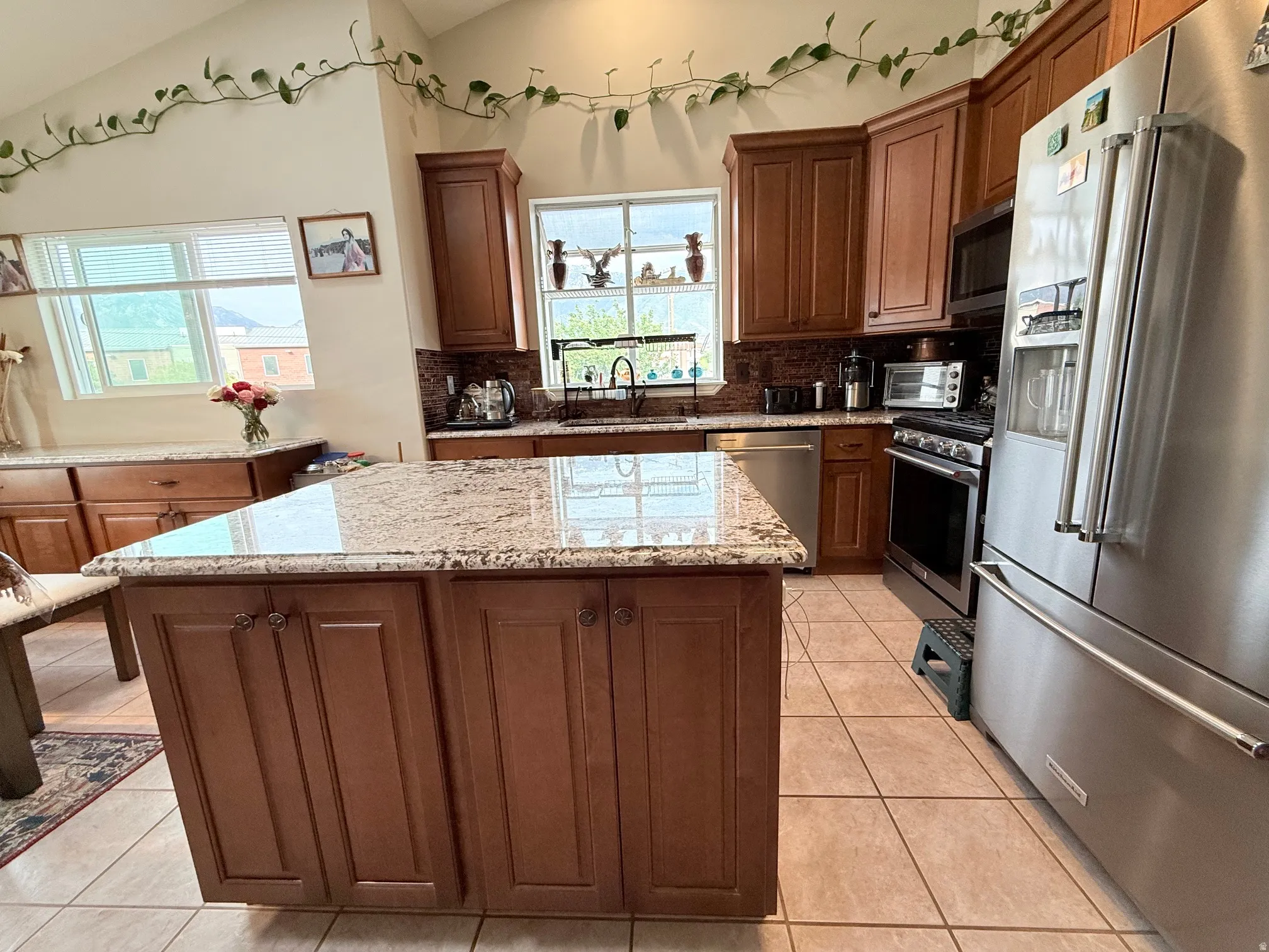 Kitchen featuring a central island with a granite countertop, wood cabinetry, stainless steel appliances, and tile flooring