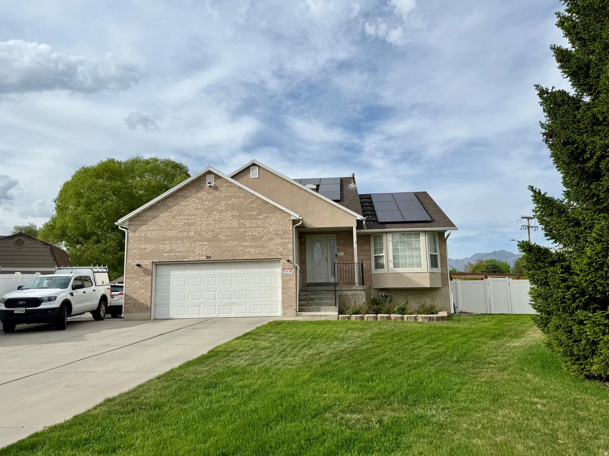 Two-story residence featuring a brick facade, attached garage, and a bay window