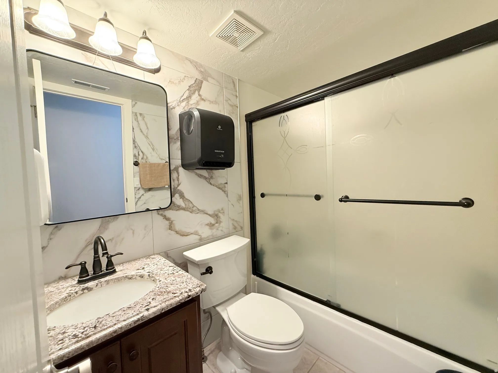 Bathroom vanity with a granite countertop, undermount sink, and dark bronze faucet