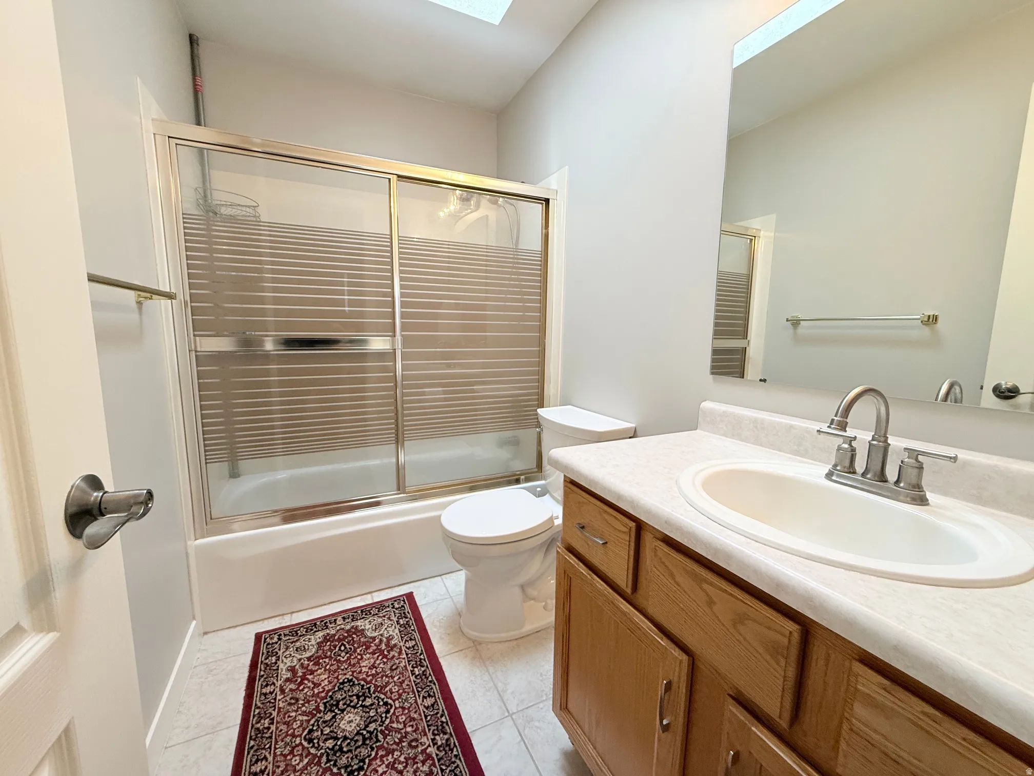 Bathroom featuring a vanity with wood-finish cabinetry, an integrated sink, and a light-toned countertop