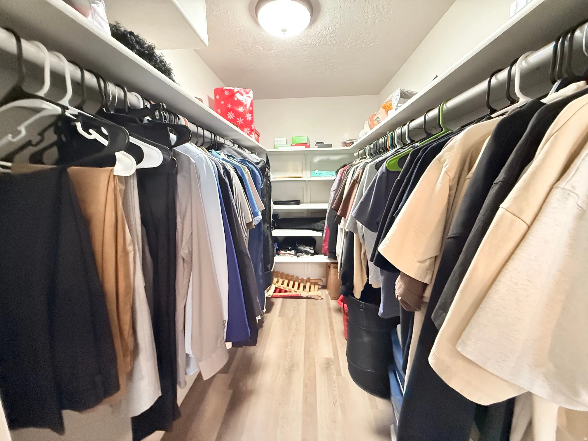 Walk-in closet featuring light wood-finish flooring, recessed shelving, and a ceiling-mounted light fixture