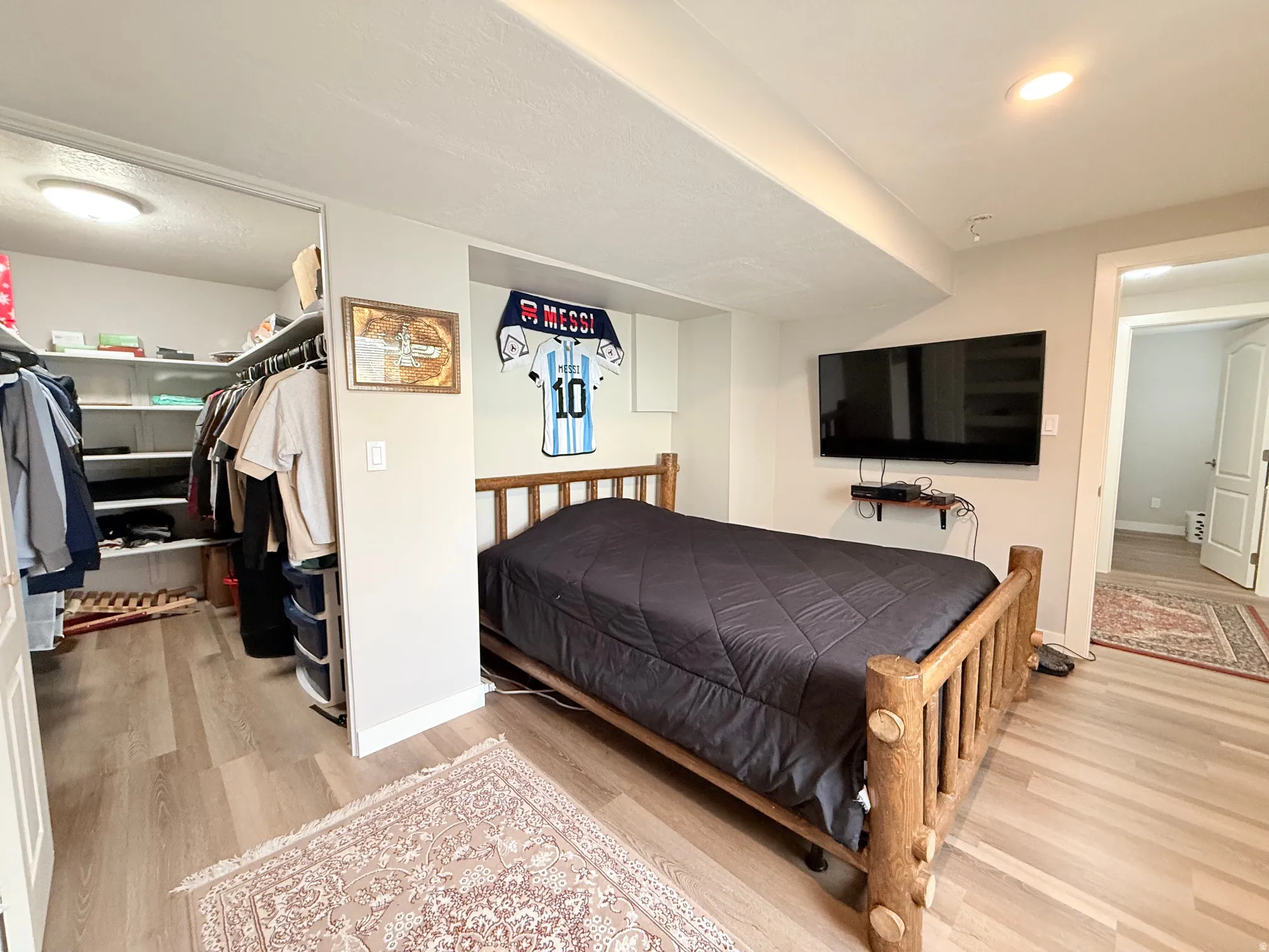 Bedroom featuring wood-finish flooring, a built-in closet with shelving and hanging rods, recessed lighting, and an additional doorway