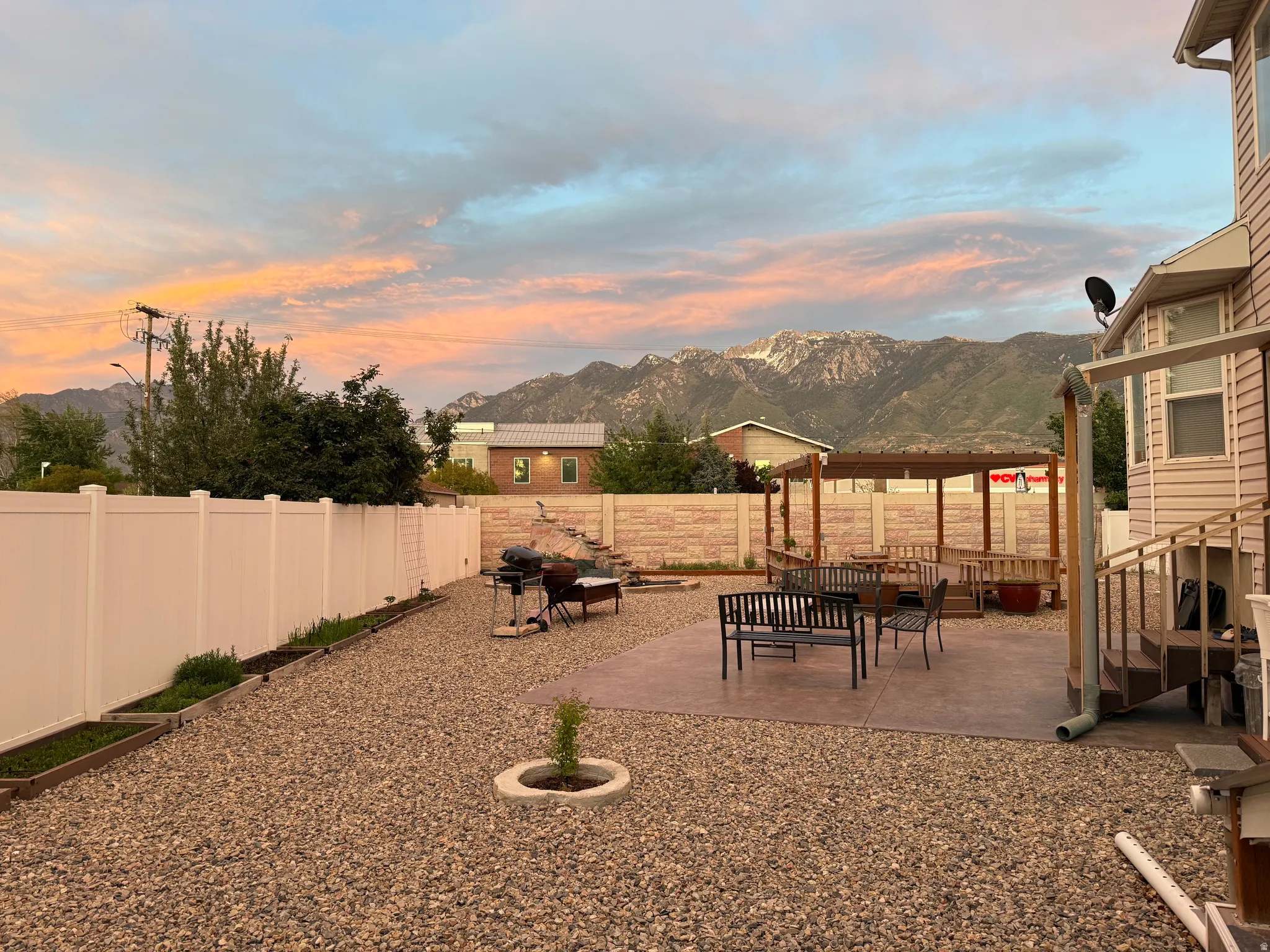 Expansive backyard featuring a gravel-covered area, a patterned concrete patio, and a covered pergola