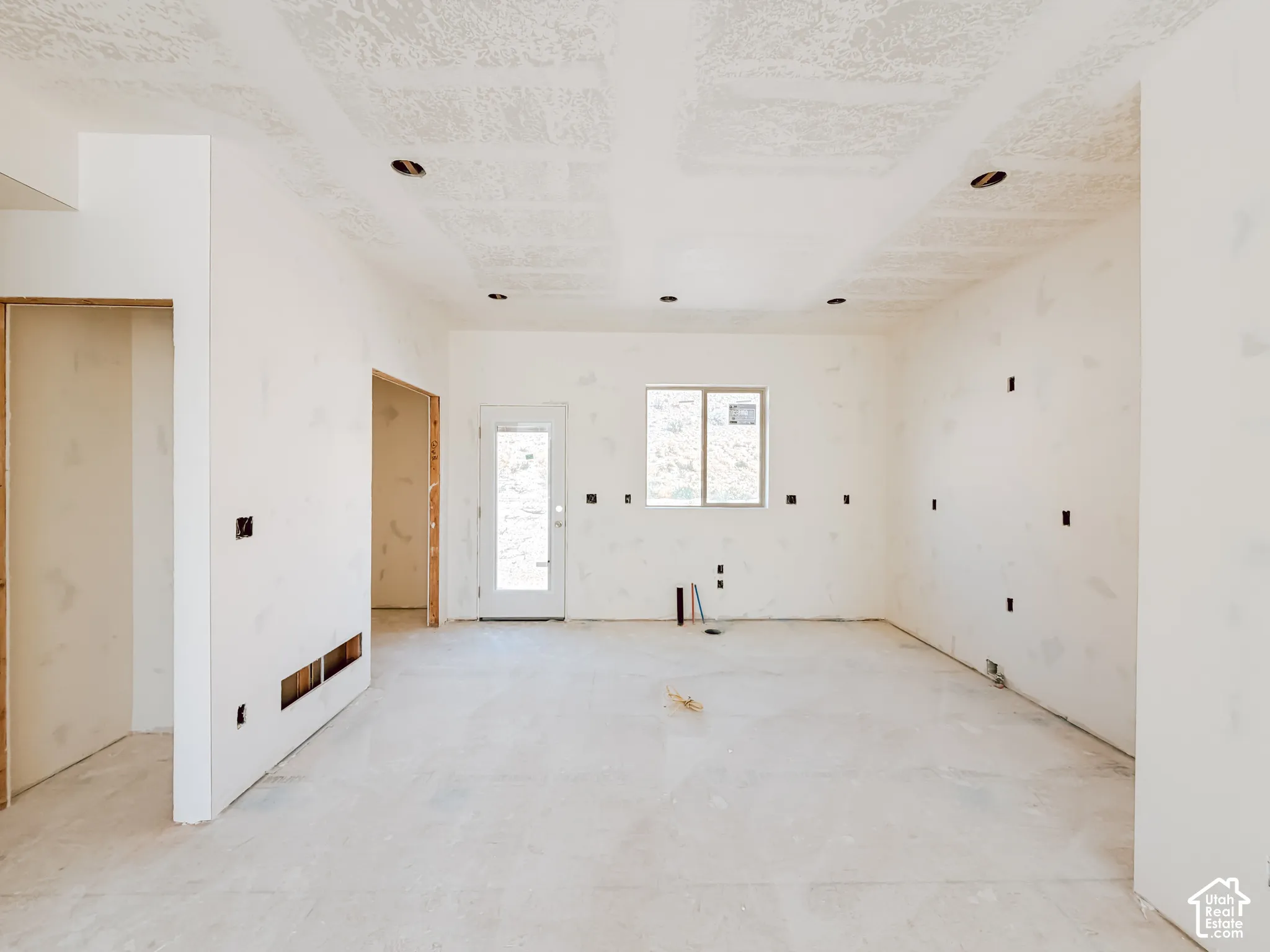 Open-concept interior featuring recessed lighting, smooth-finish ceilings, an exterior door, and large window