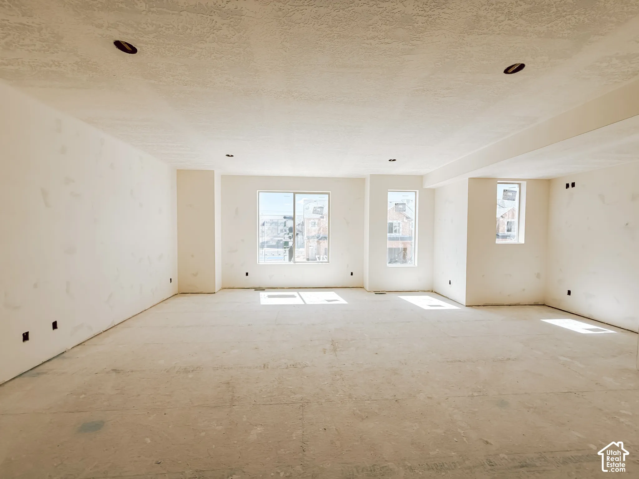 Expansive open-concept room featuring recessed lighting, smooth-finish walls, and multiple windows providing natural illumination