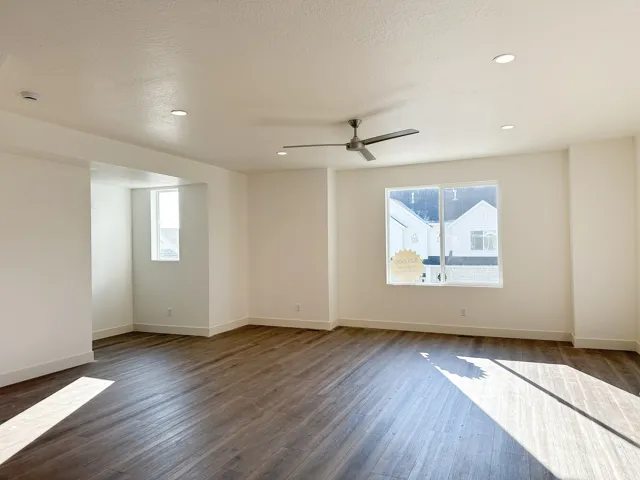 Spacious room featuring wood-finish flooring, recessed lighting, a modern ceiling fan, and multiple windows with white trim