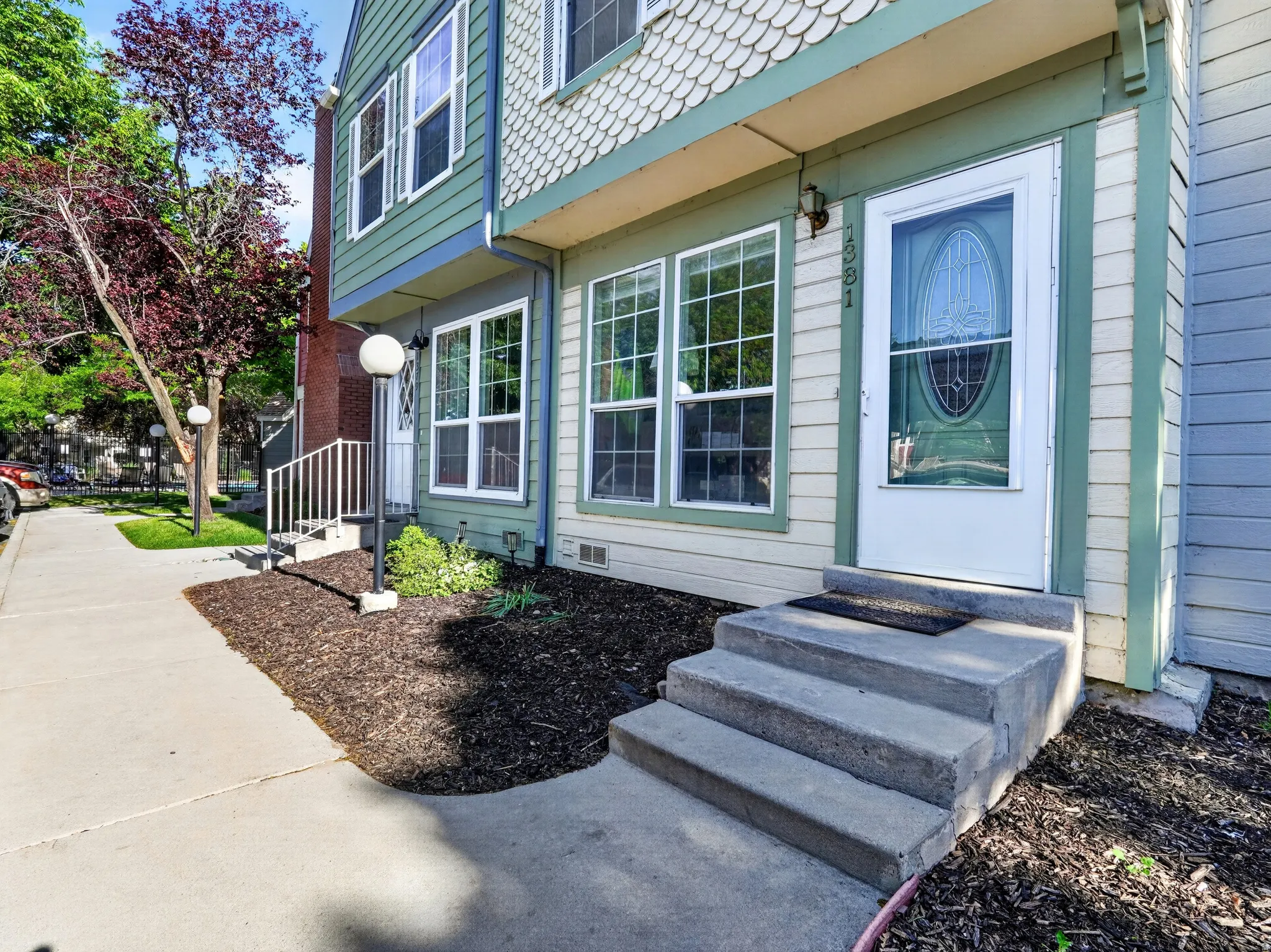 Front entrance featuring concrete steps, a white storm door with decorative glass, and a large window with white muntins