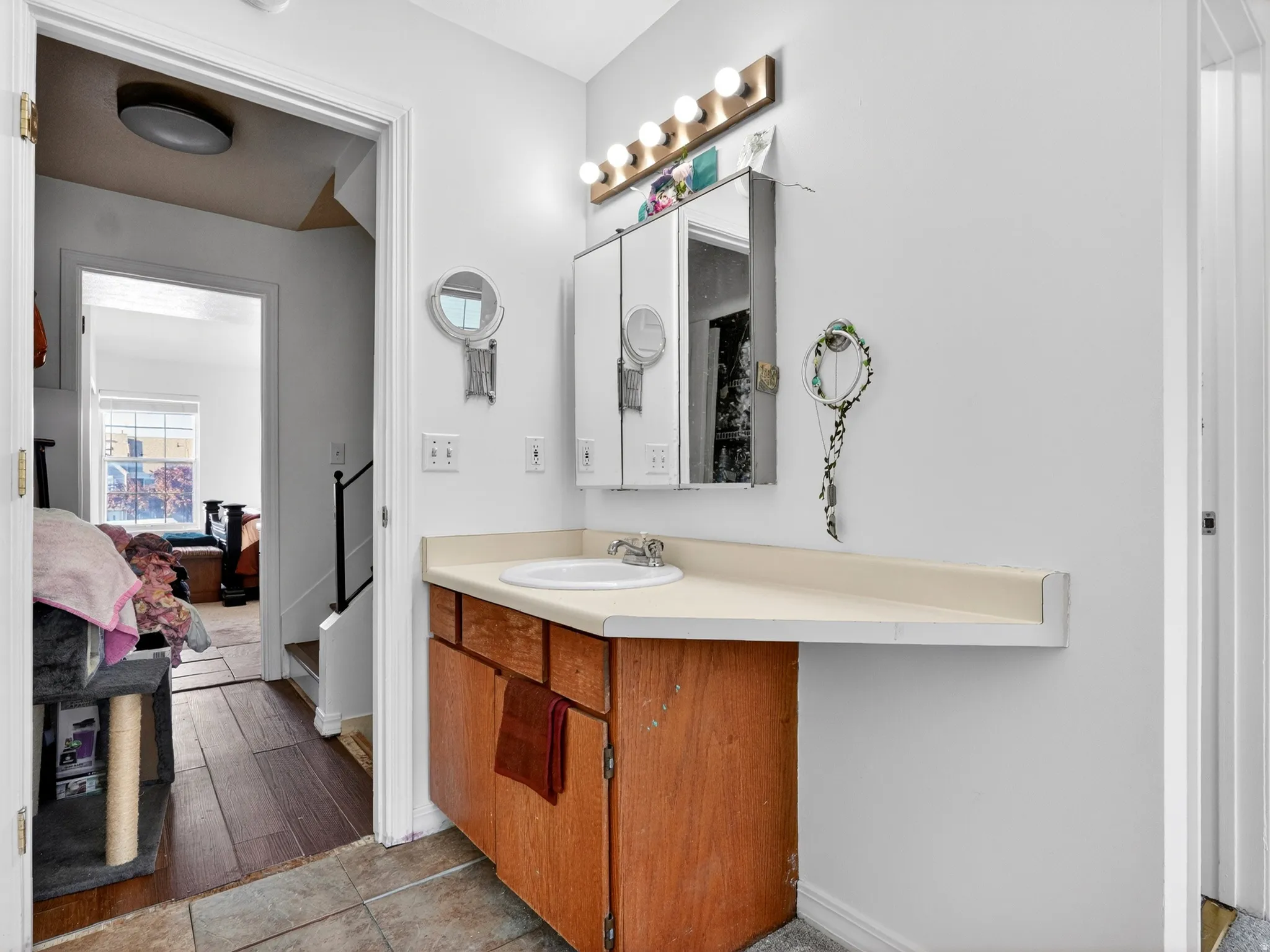 Bathroom vanity featuring a white basin, light-toned countertop, and wood-finish cabinetry