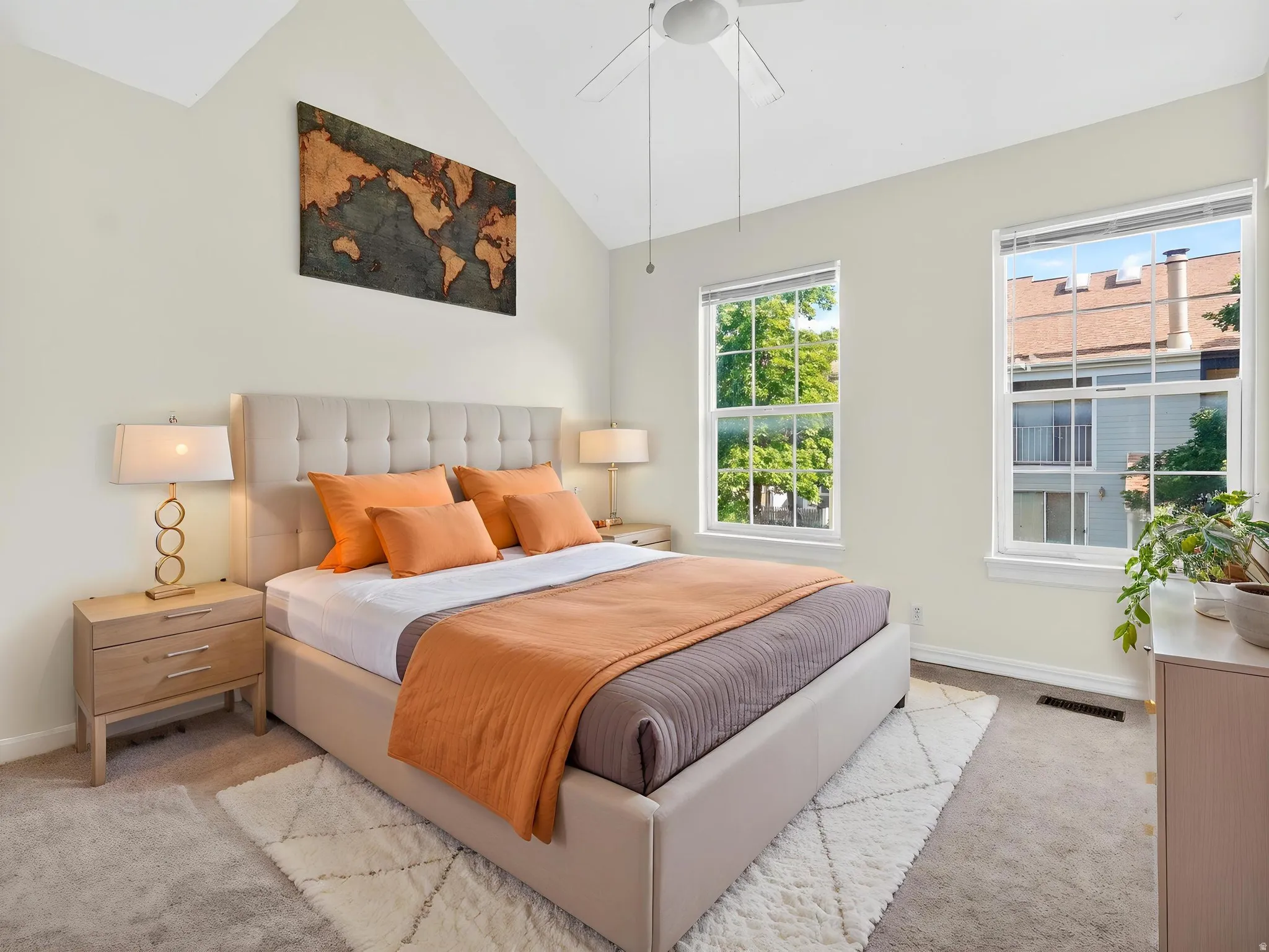Bedroom featuring vaulted ceilings, plush carpeting, dual windows, and a ceiling fan