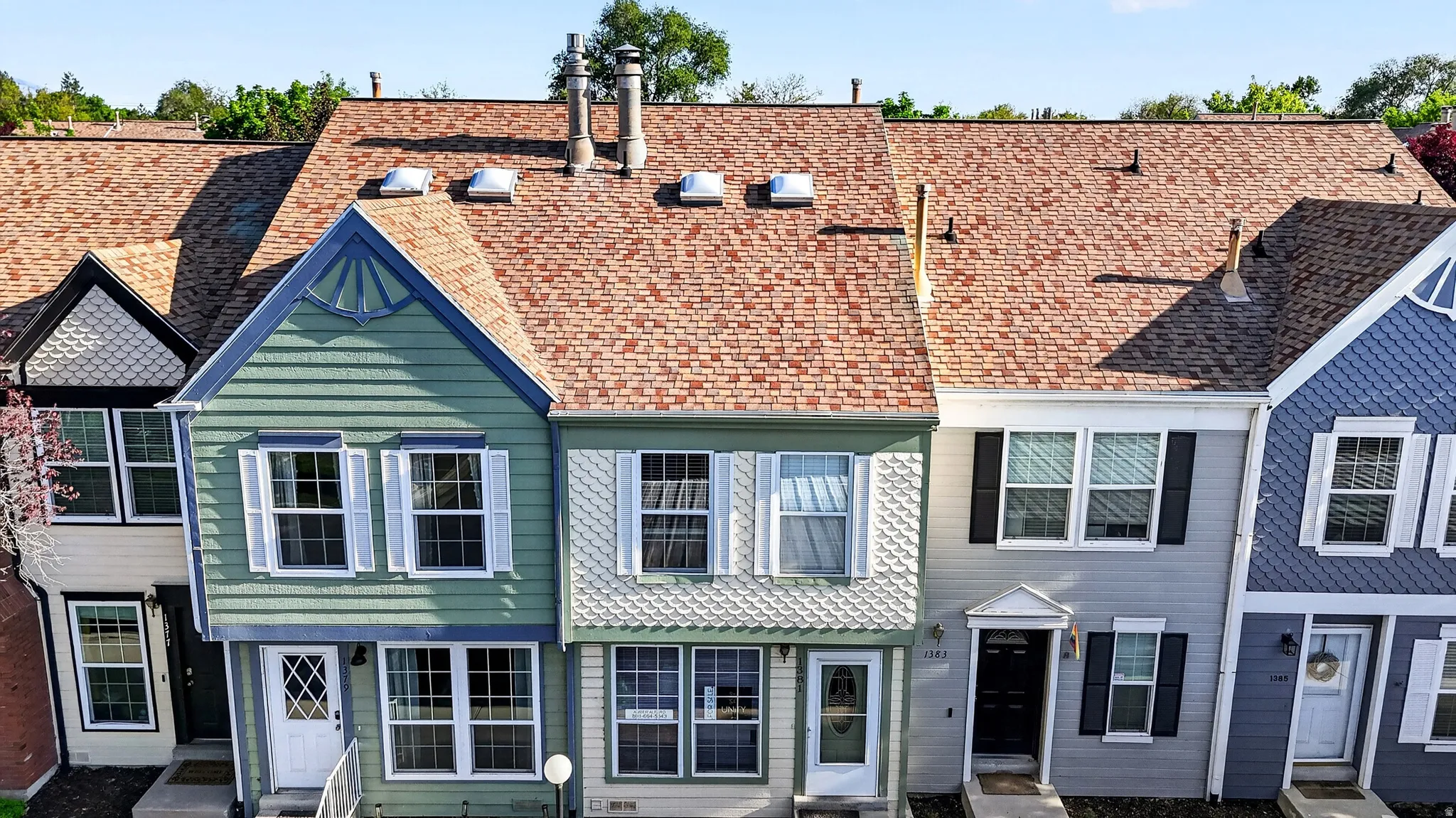 Row of residences featuring varied exterior siding, gabled rooflines, and individual entryways