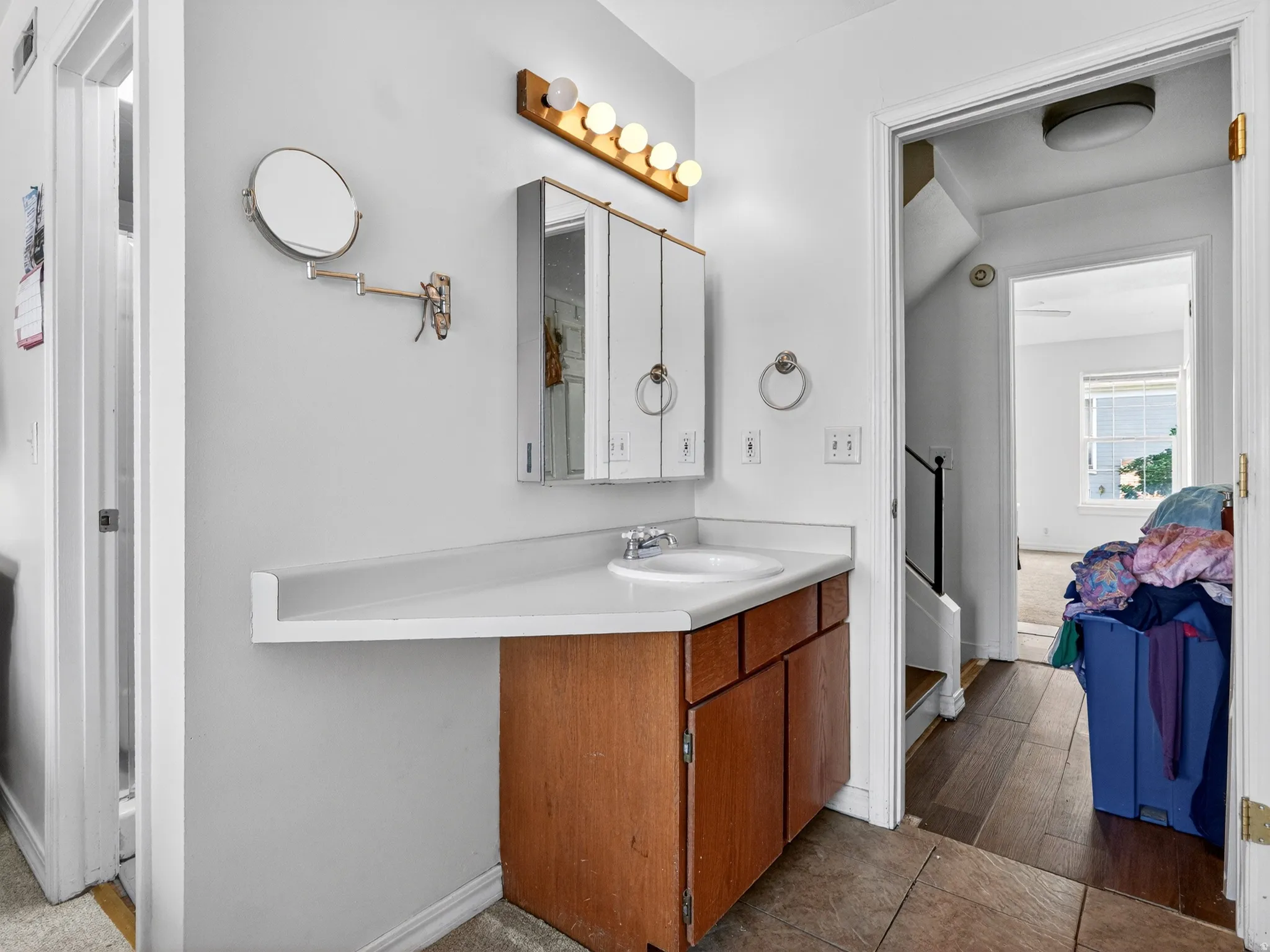 Bathroom vanity featuring a single basin sink, laminate countertop, and wood-finish cabinetry