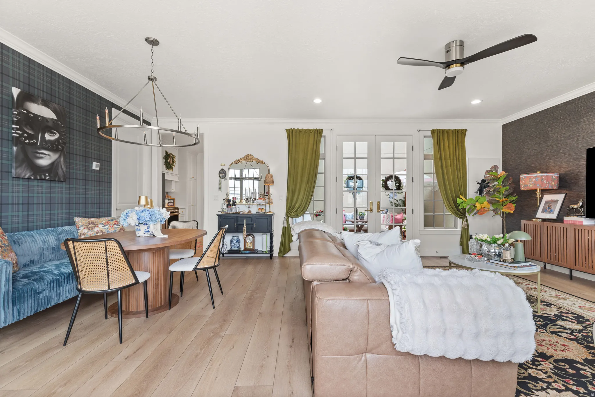 Open-concept living space featuring wood-finish flooring, a contemporary chandelier, crown molding, and recessed lighting