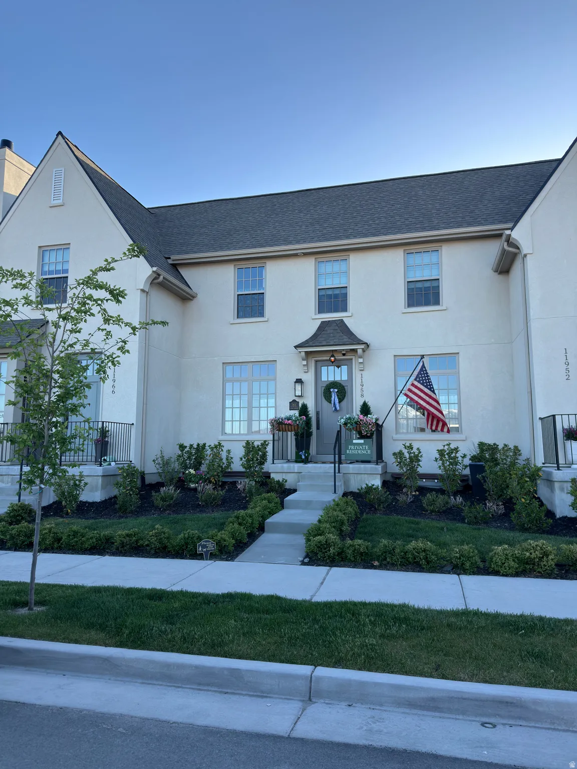 Cream stucco exterior featuring a gabled roofline, dark shingles, and multiple double-hung windows