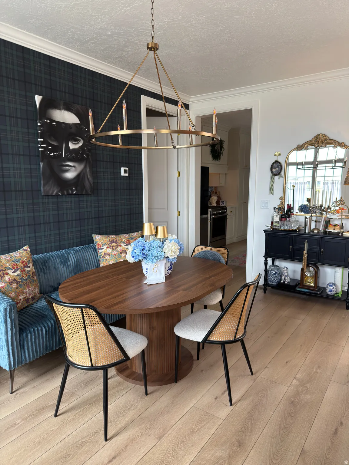 Dining area featuring light wood-finish flooring, dark plaid wallcovering, and a brass chandelier